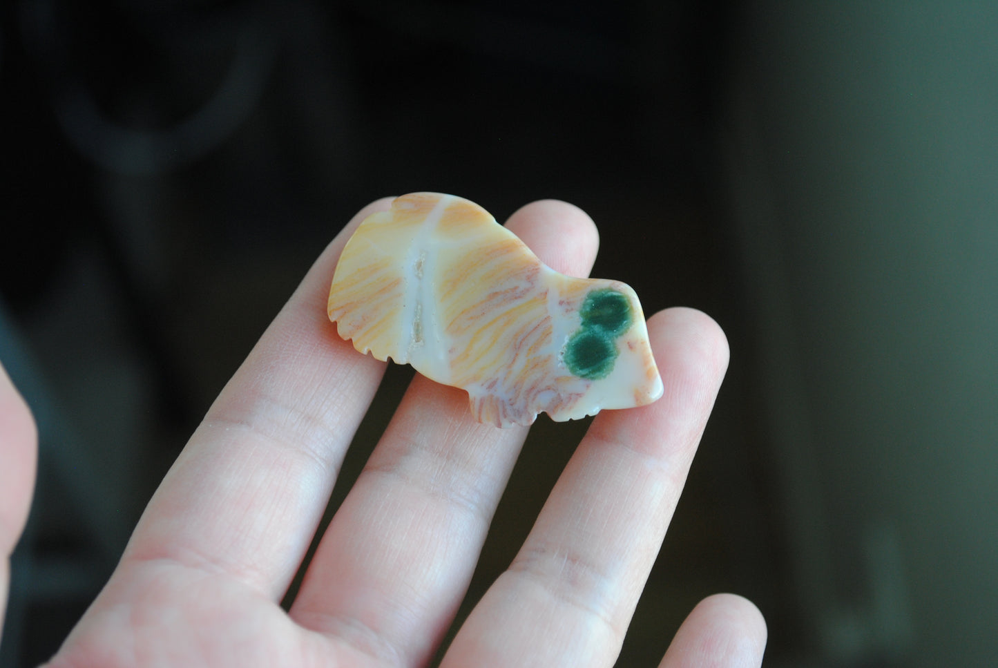 Hand holding a small carved frog stone