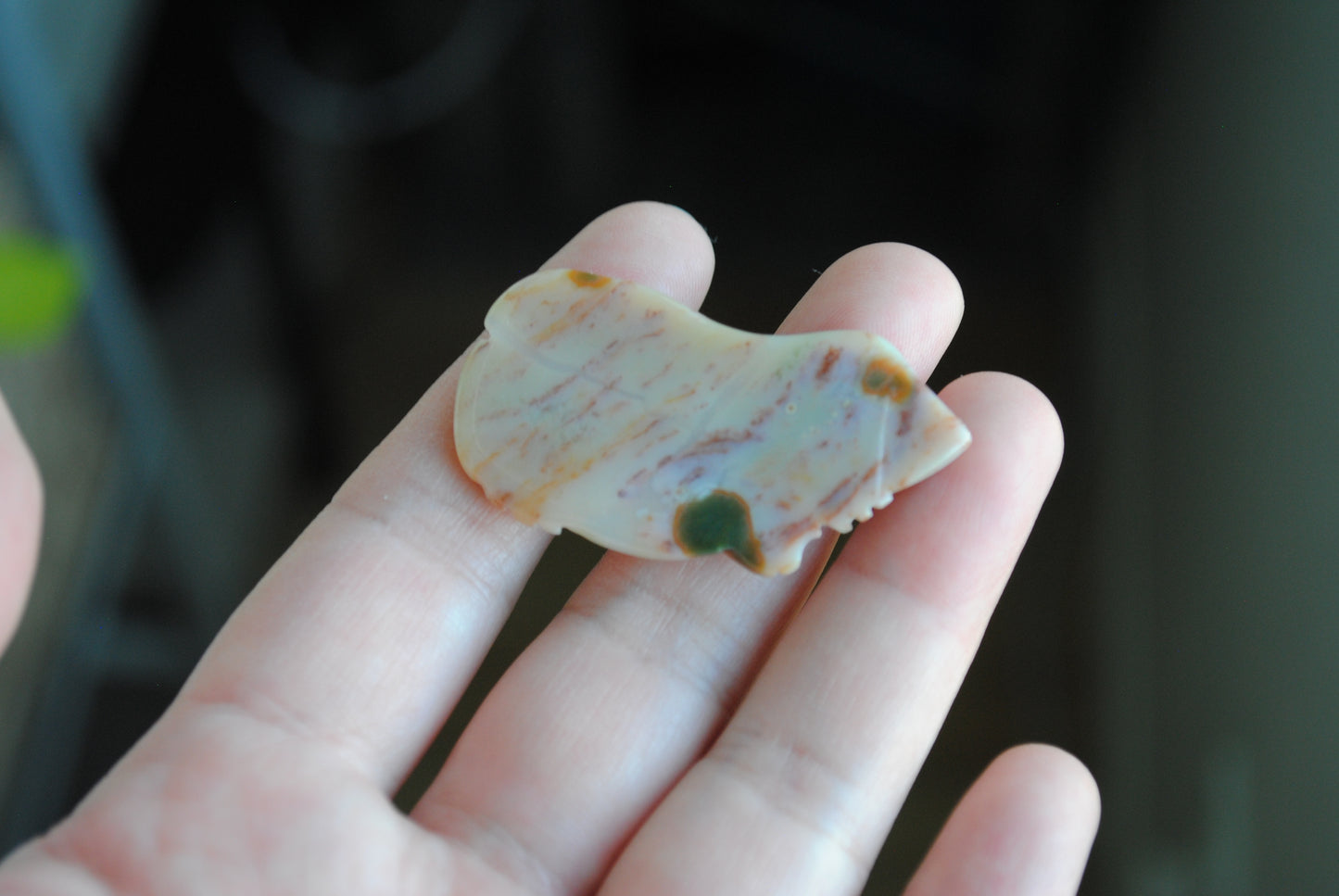 Carved stone frog held in a hand against a dark background
