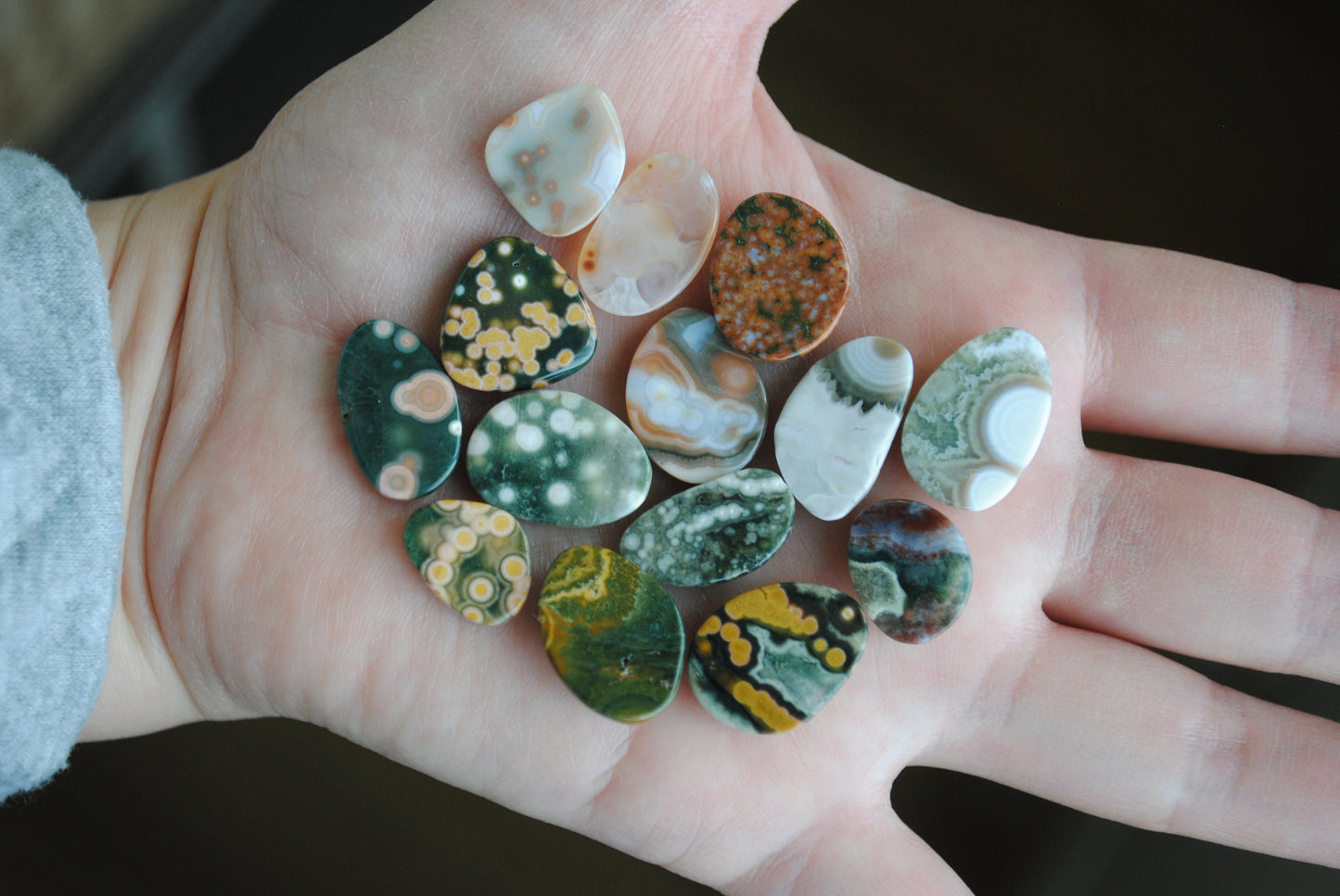 Hand holding a collection of colorful marbled stones.