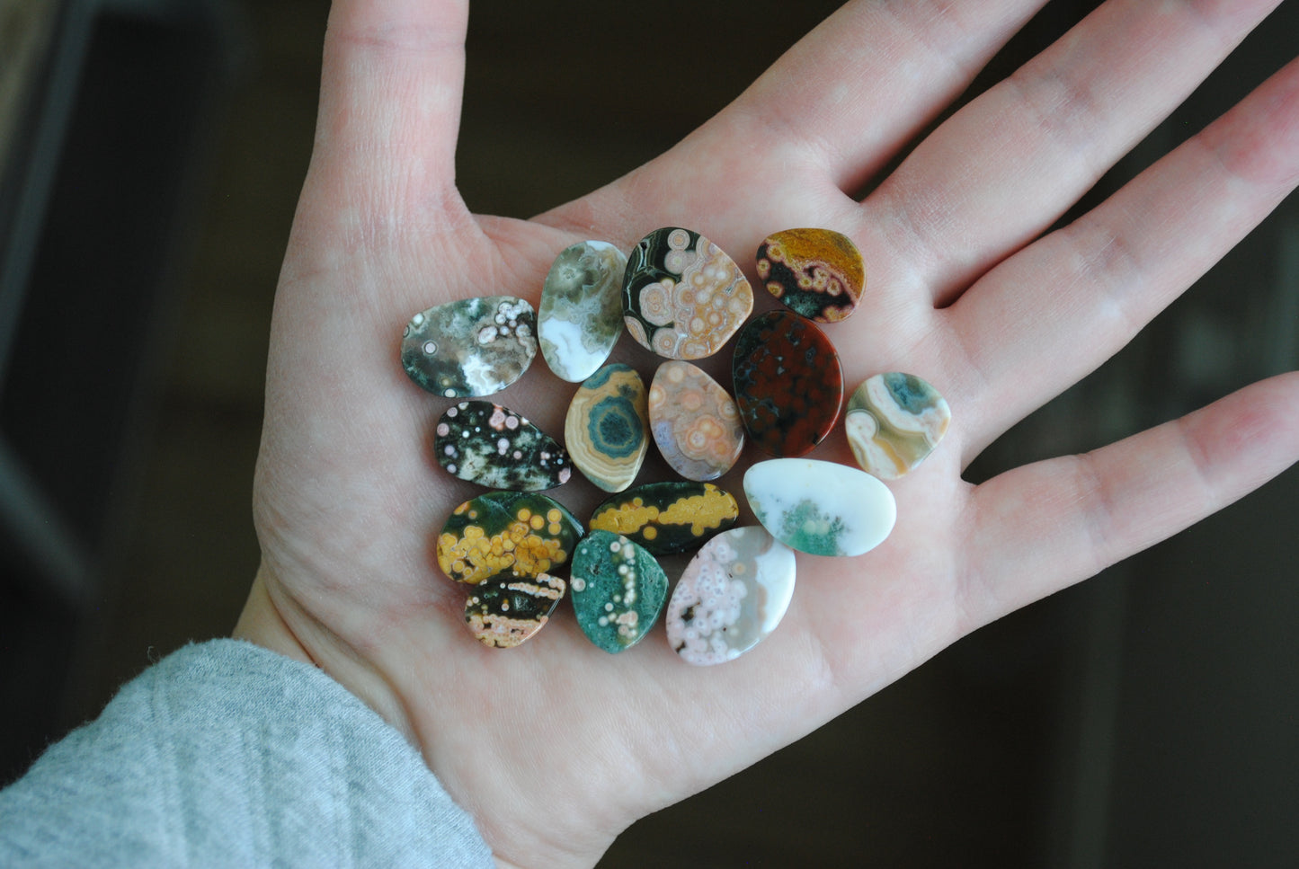 Hand holding a collection of small, multicolored stones with a blurred background