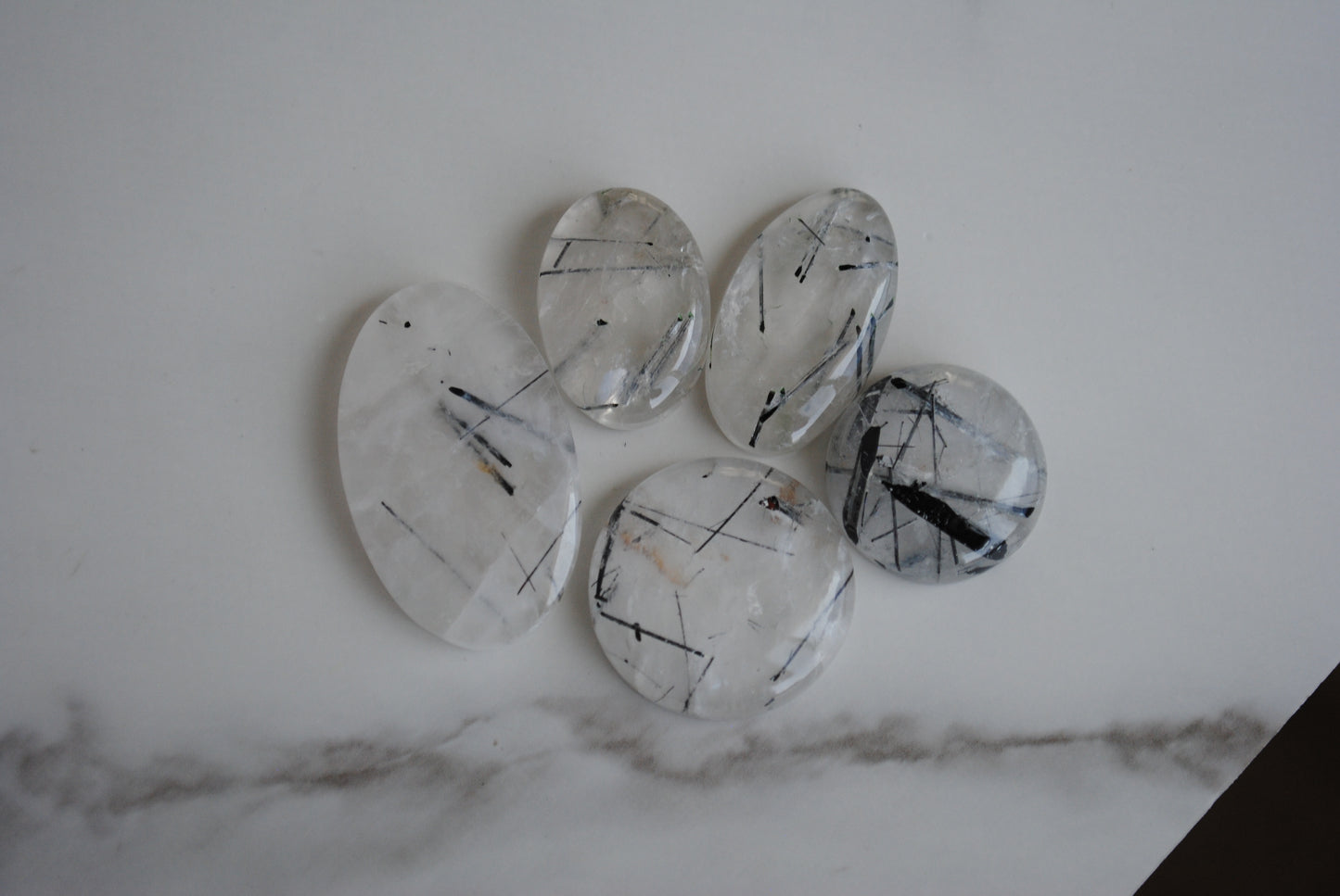 Tourmalinated quartz cabochons on light background