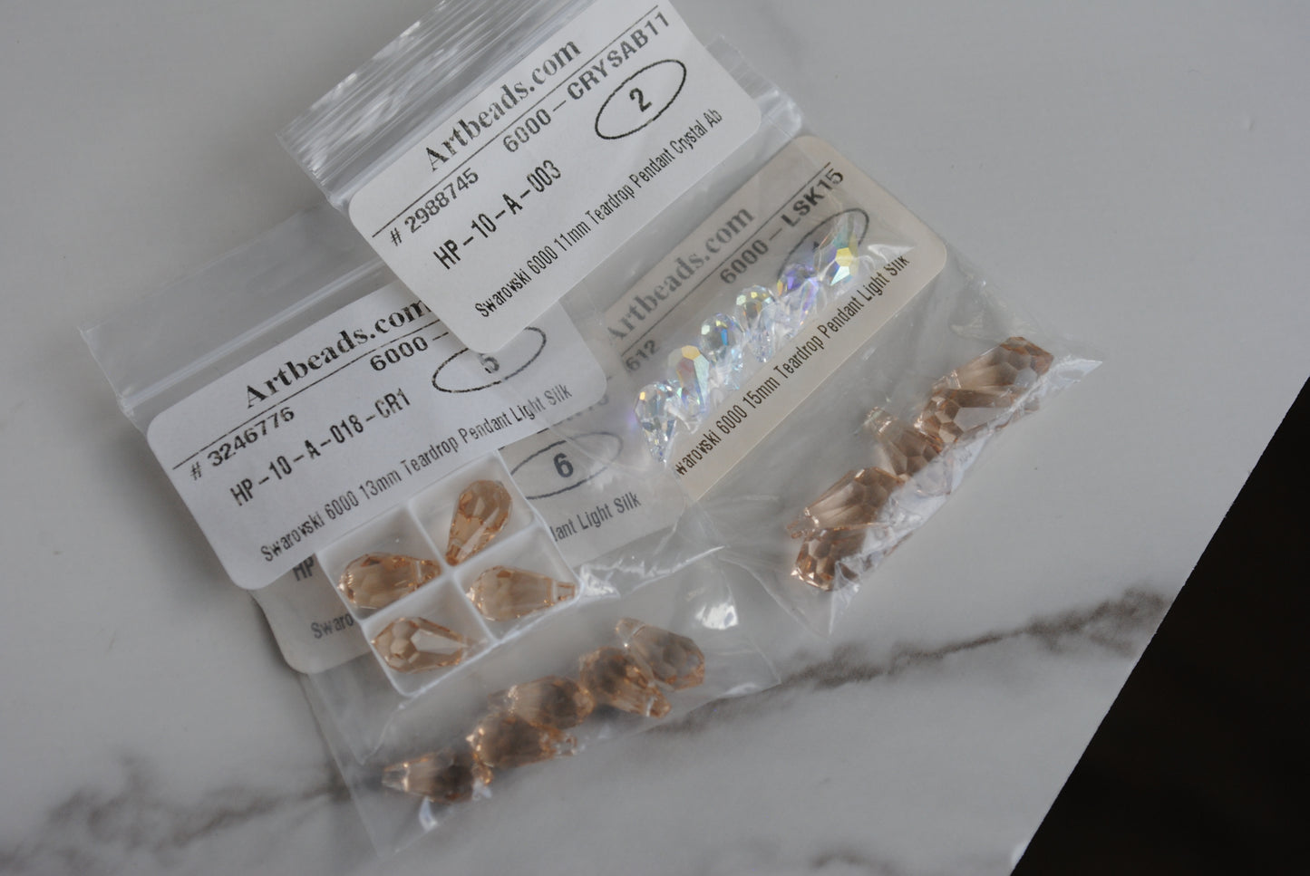 Swarovski teardrop in bags on light background