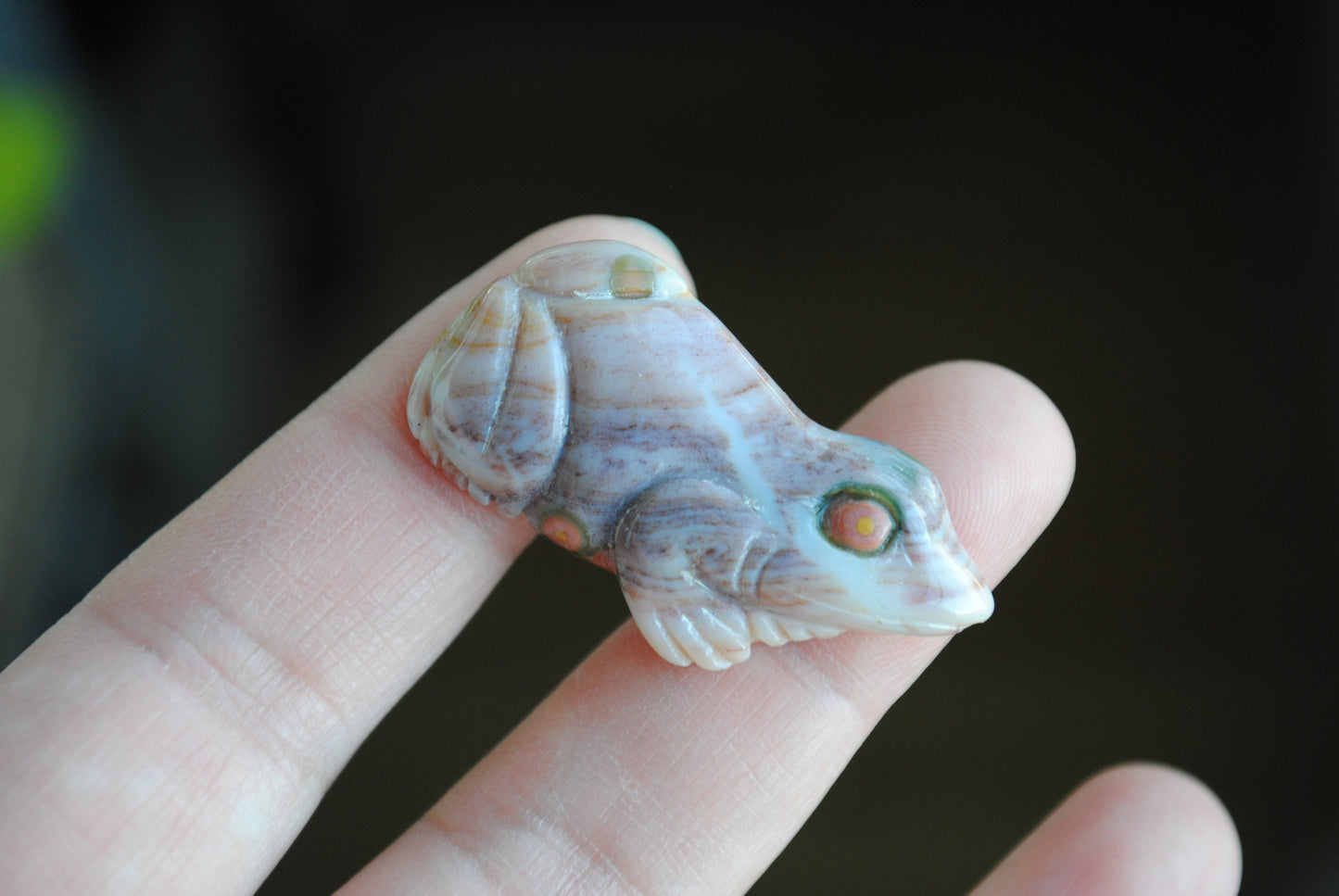 Carved stone frog held in a hand against a dark background