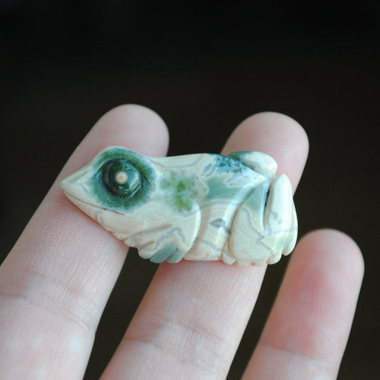 Carved stone frog held in a hand against a dark background