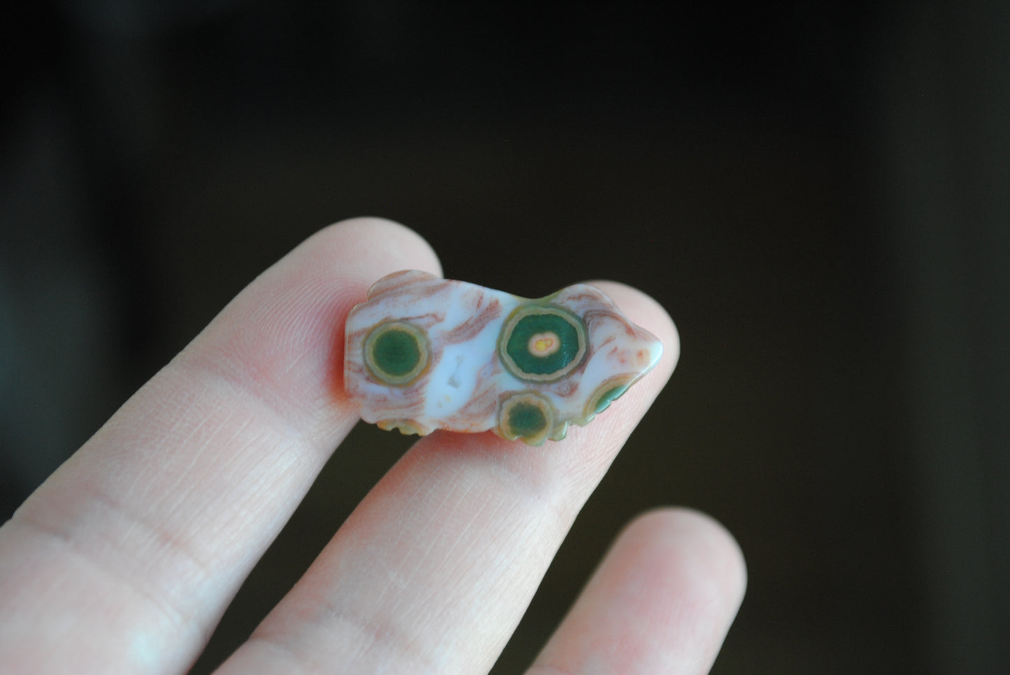 Small stone carving of a frog held in a hand against a dark background