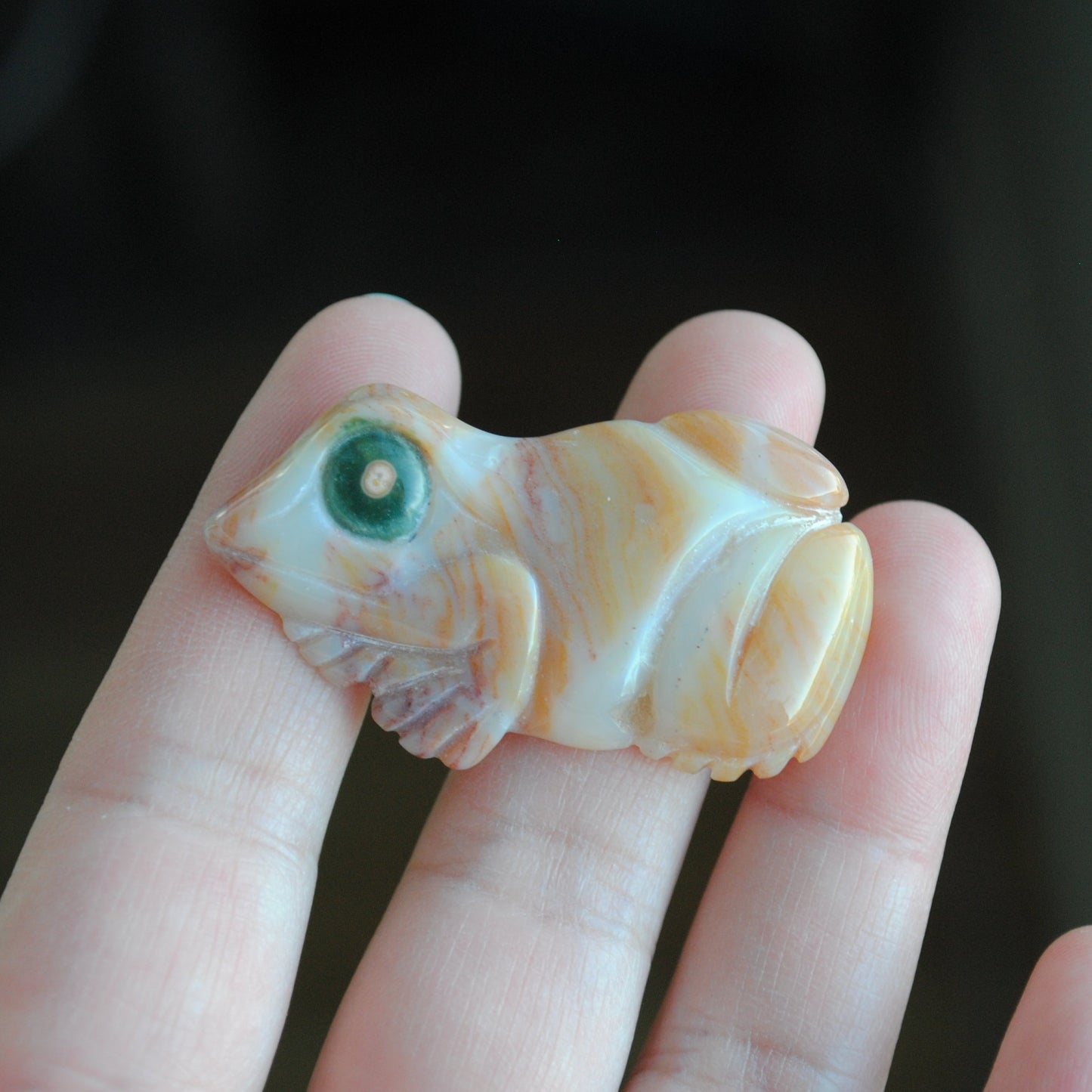 Hand holding a small carved frog stone 