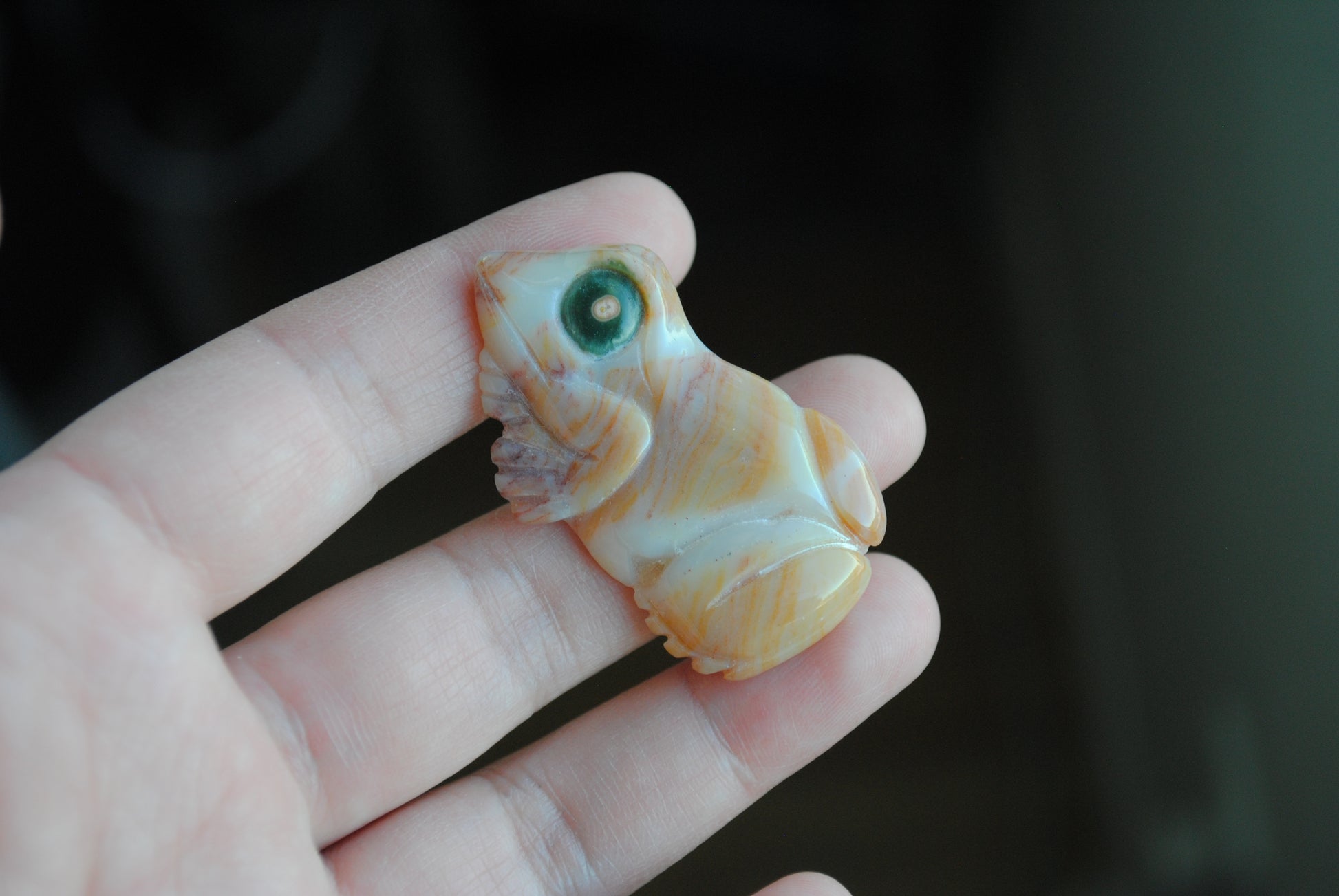 Hand holding a small carved frog stone 
