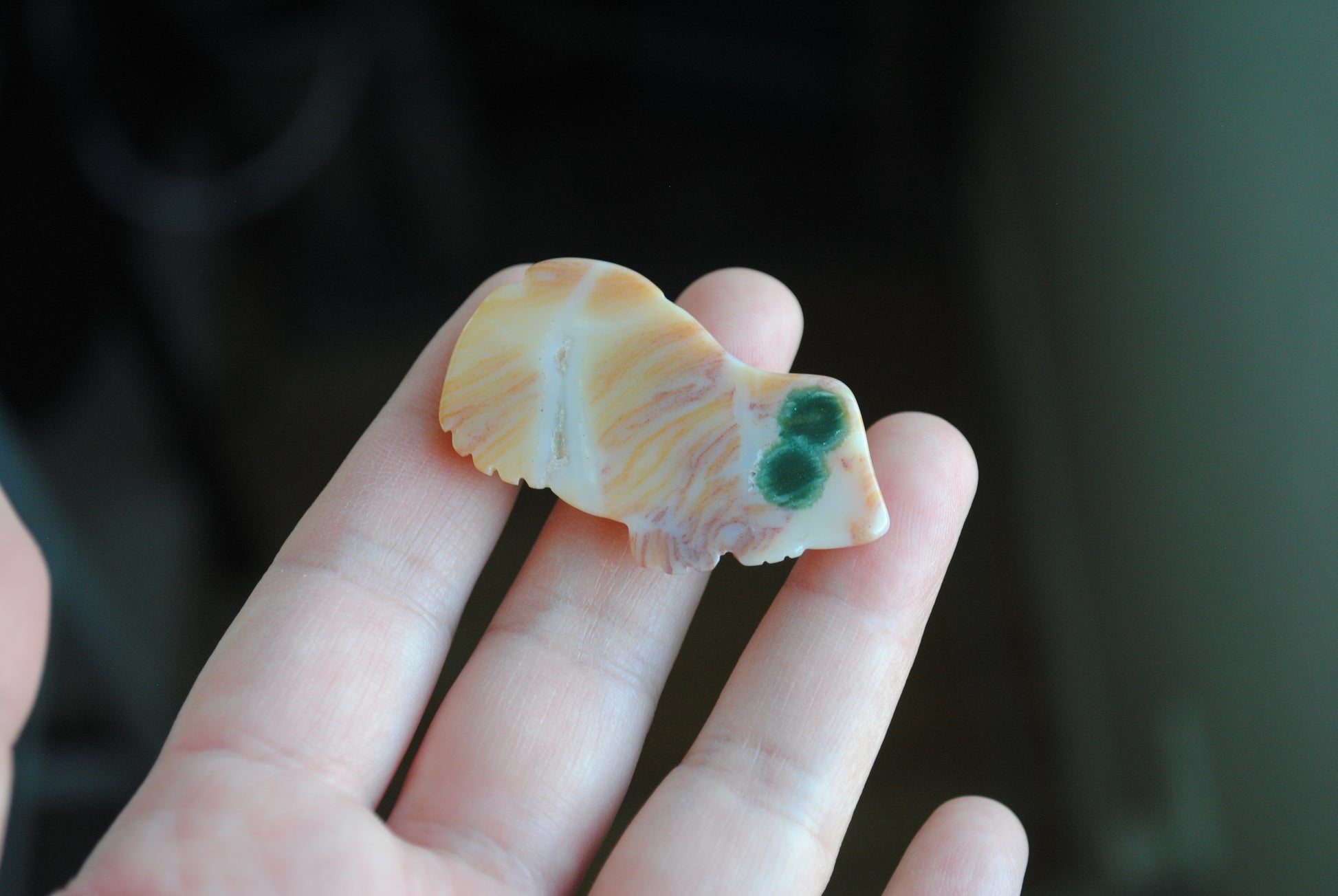 Hand holding a small carved frog stone 