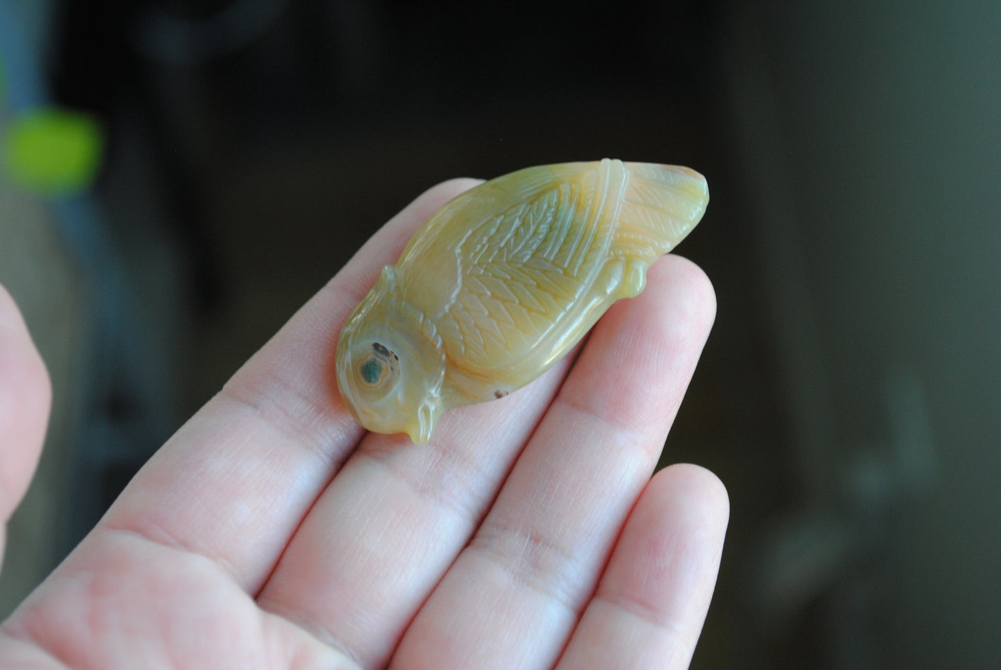 Ocean Jasper carved bird held in a hand against a blurred background
