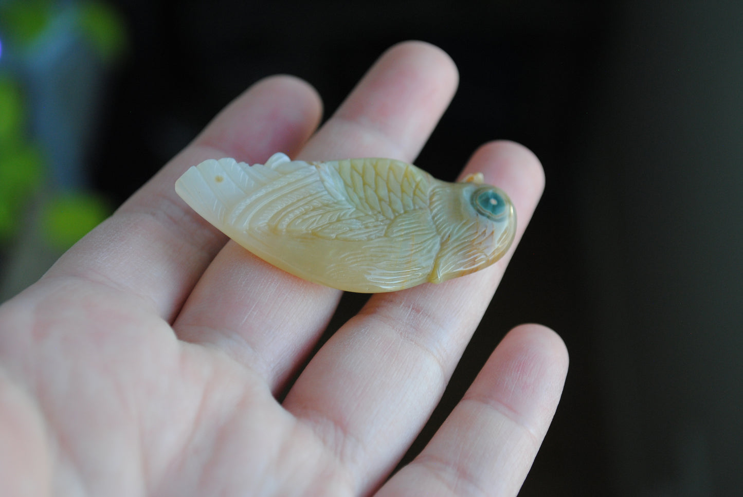 Ocean Jasper carved bird held in a hand against a blurred background