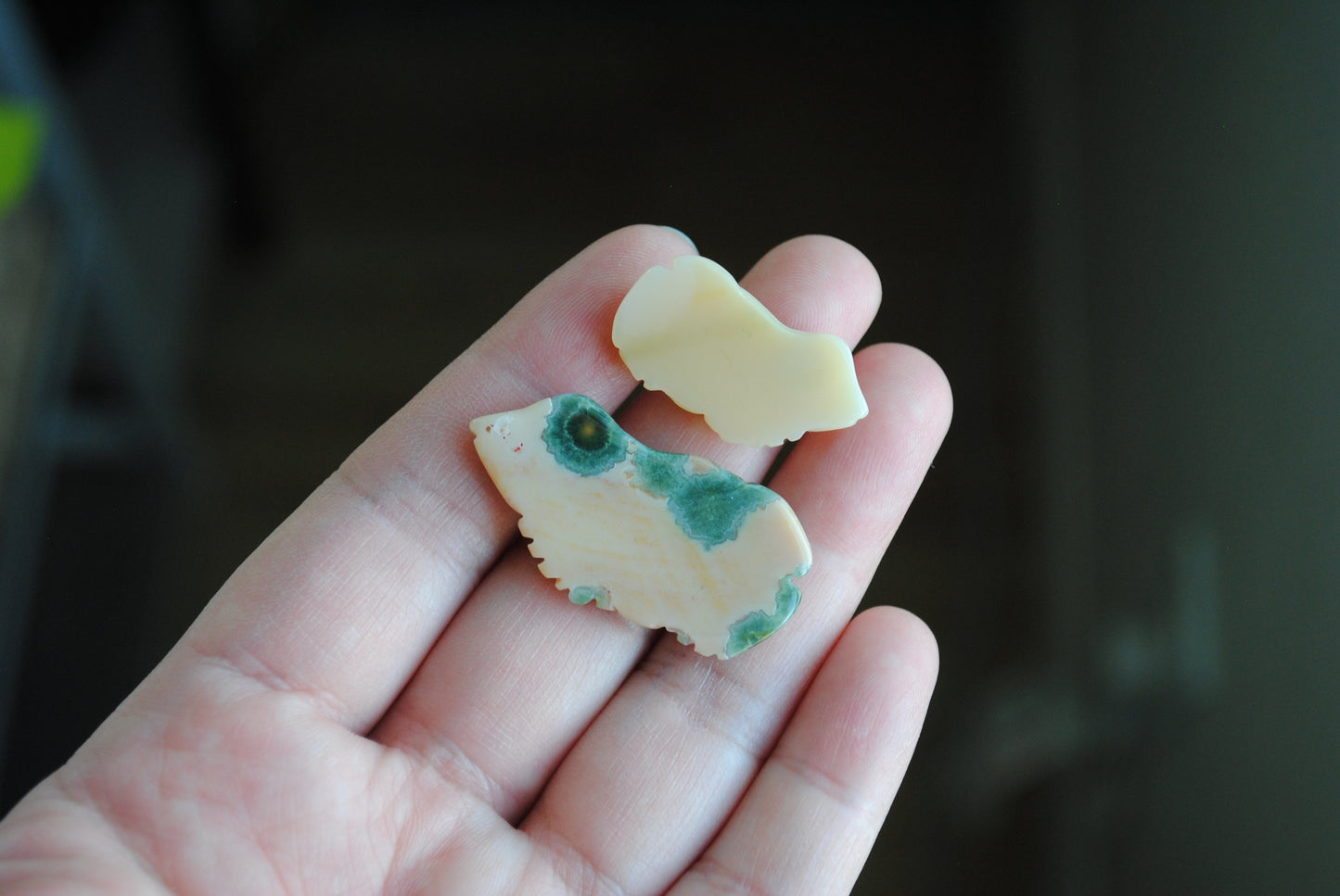 Two small stone frog carvings held in a hand against a blurred background