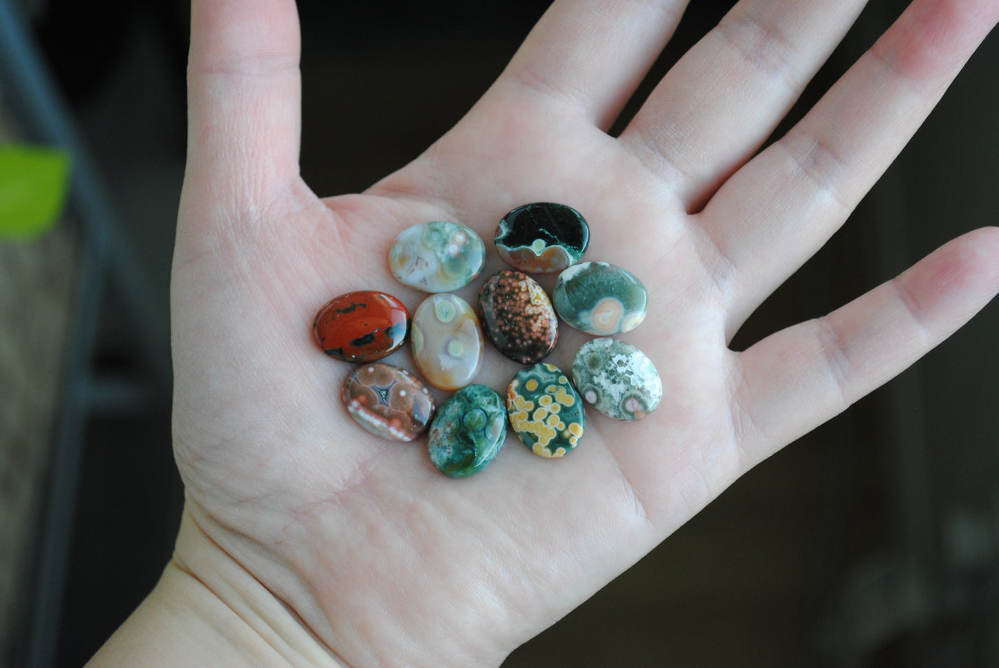 Hand holding a collection of small, colorful stones against a blurred background