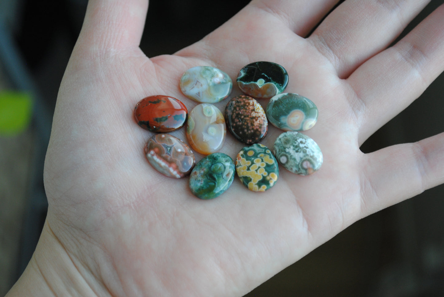 Hand holding a collection of colorful marbles against a blurred background
