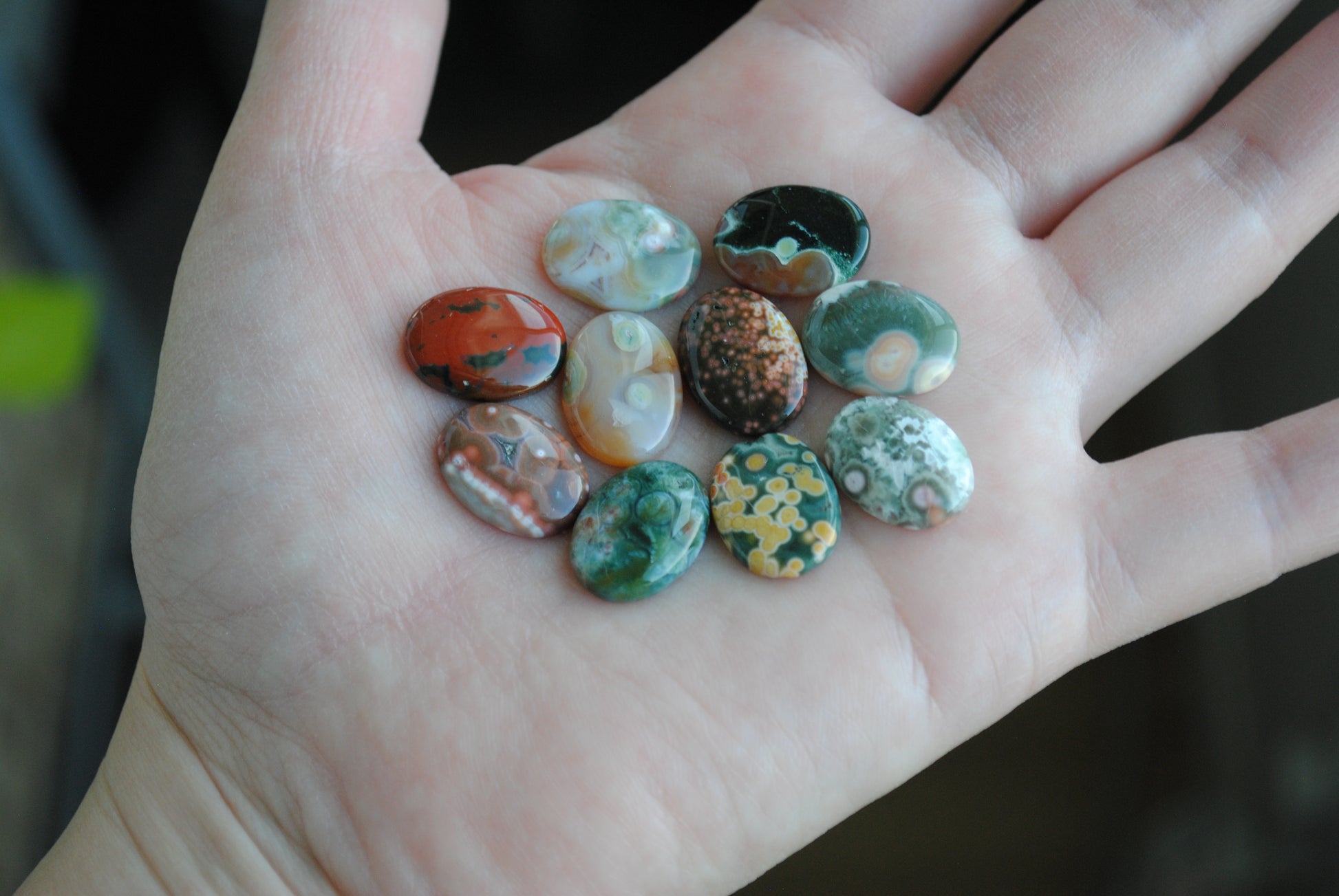 Hand holding a collection of colorful marbles against a blurred background