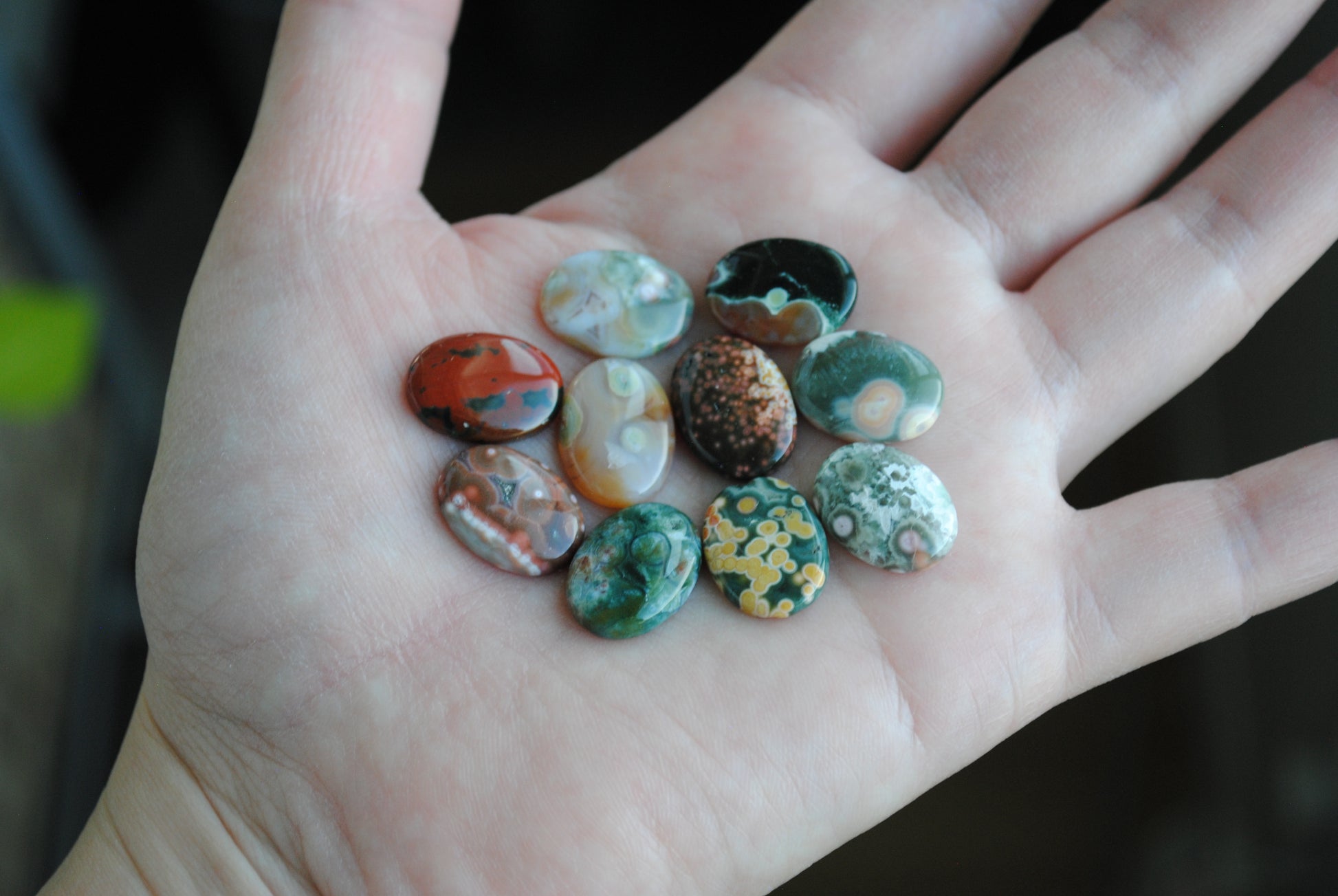 Hand holding a small collection of colorful stones with a blurred background
