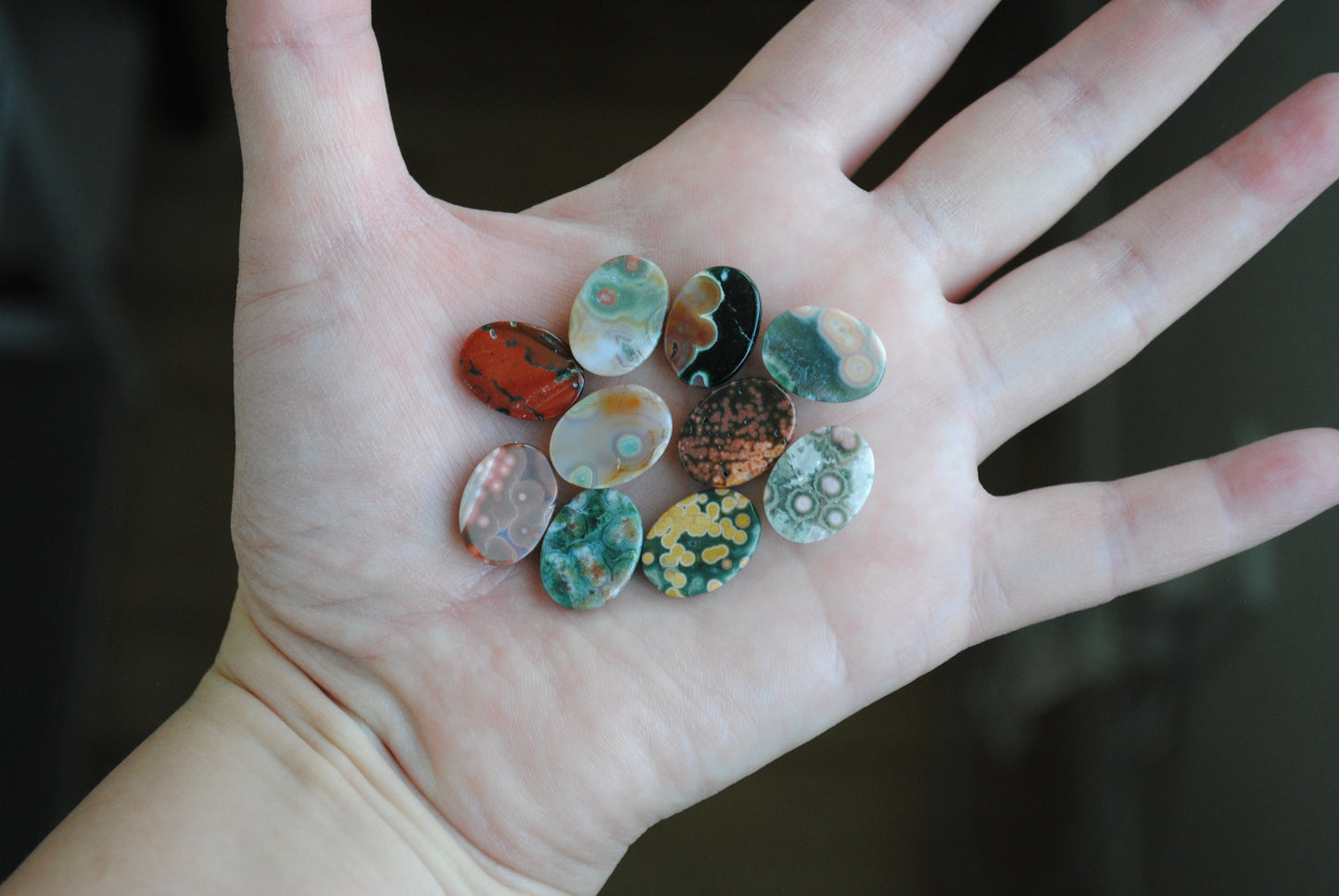 Hand holding a small collection of colorful stones with a dark background