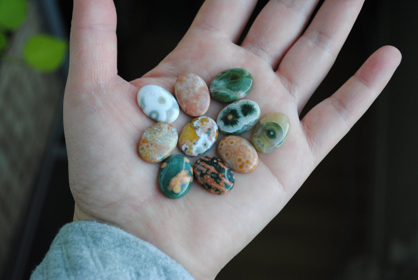 Hand holding small, multicolored stones against a dark background