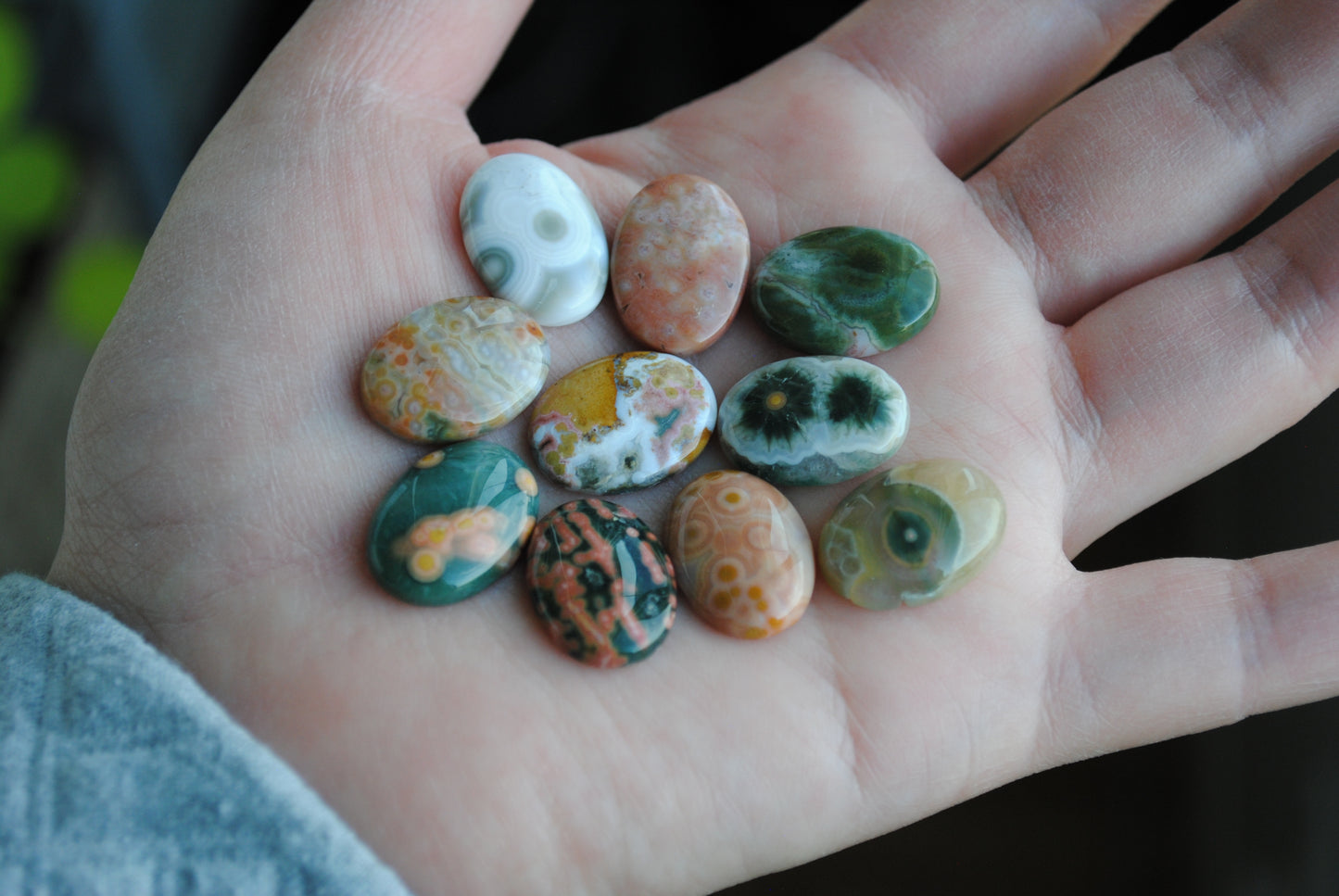 Hand holding a collection of colorful stones with a blurred background