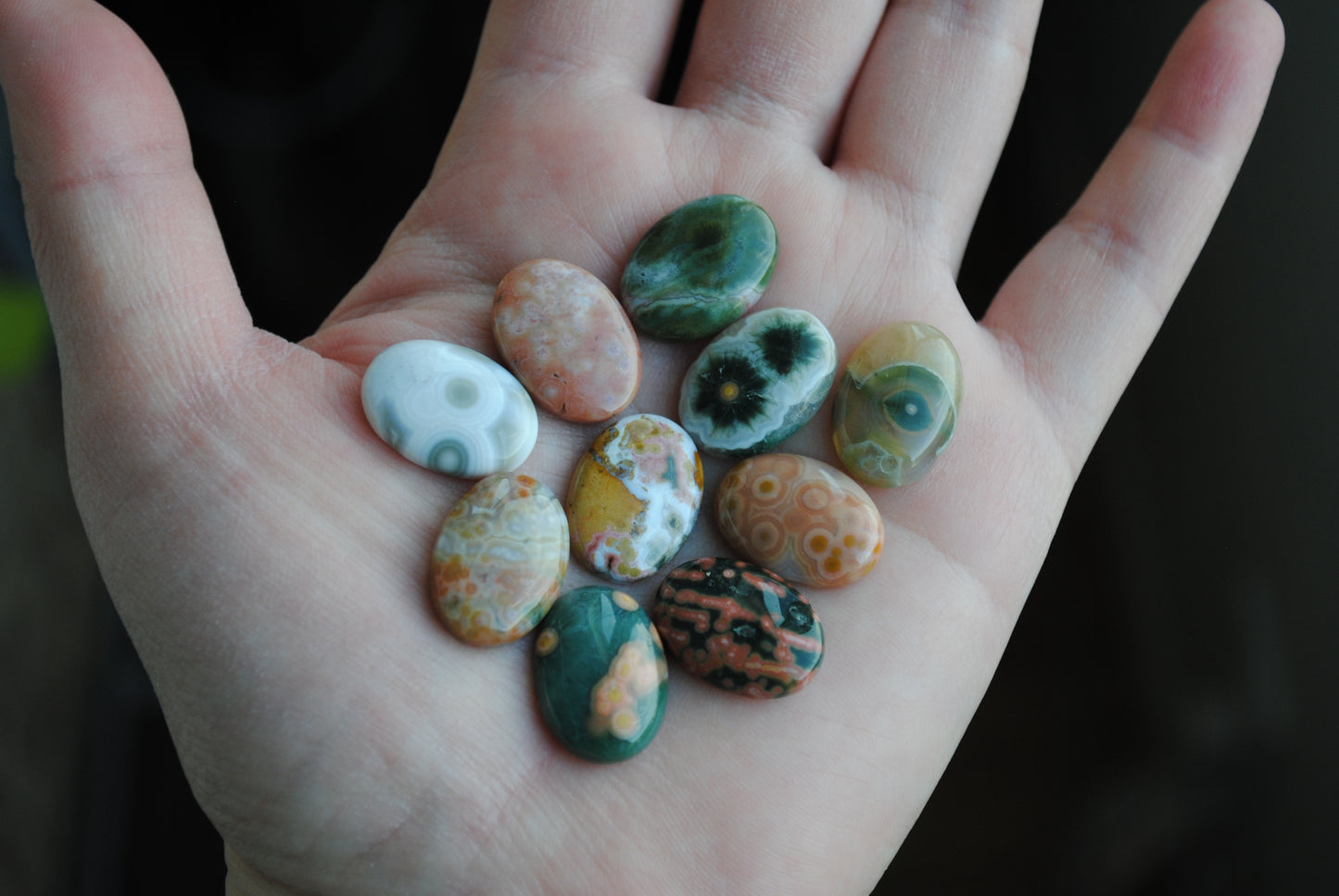 Hand holding a collection of colorful stones with a dark background
