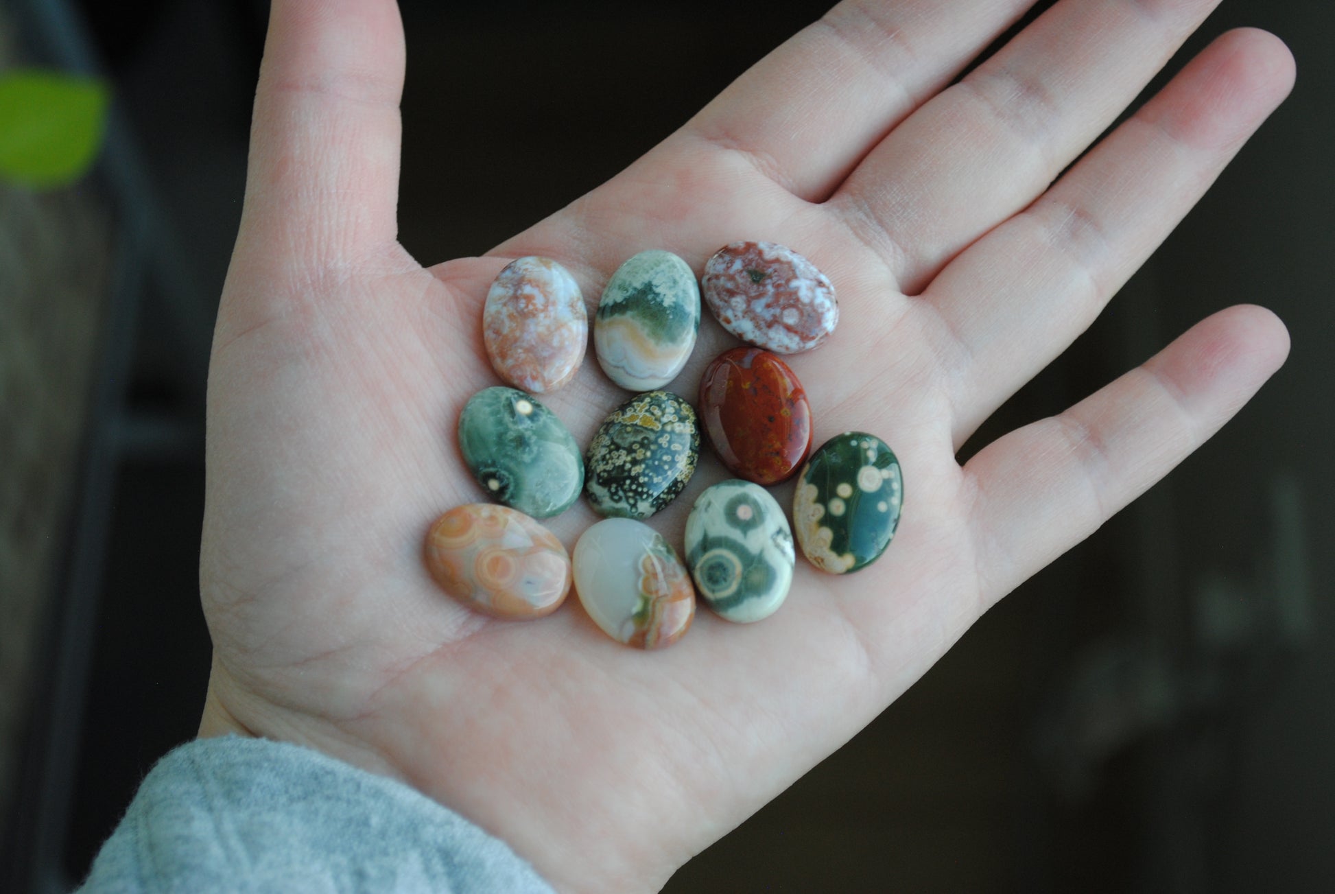 Hand holding a collection of multicolored stones against a dark background