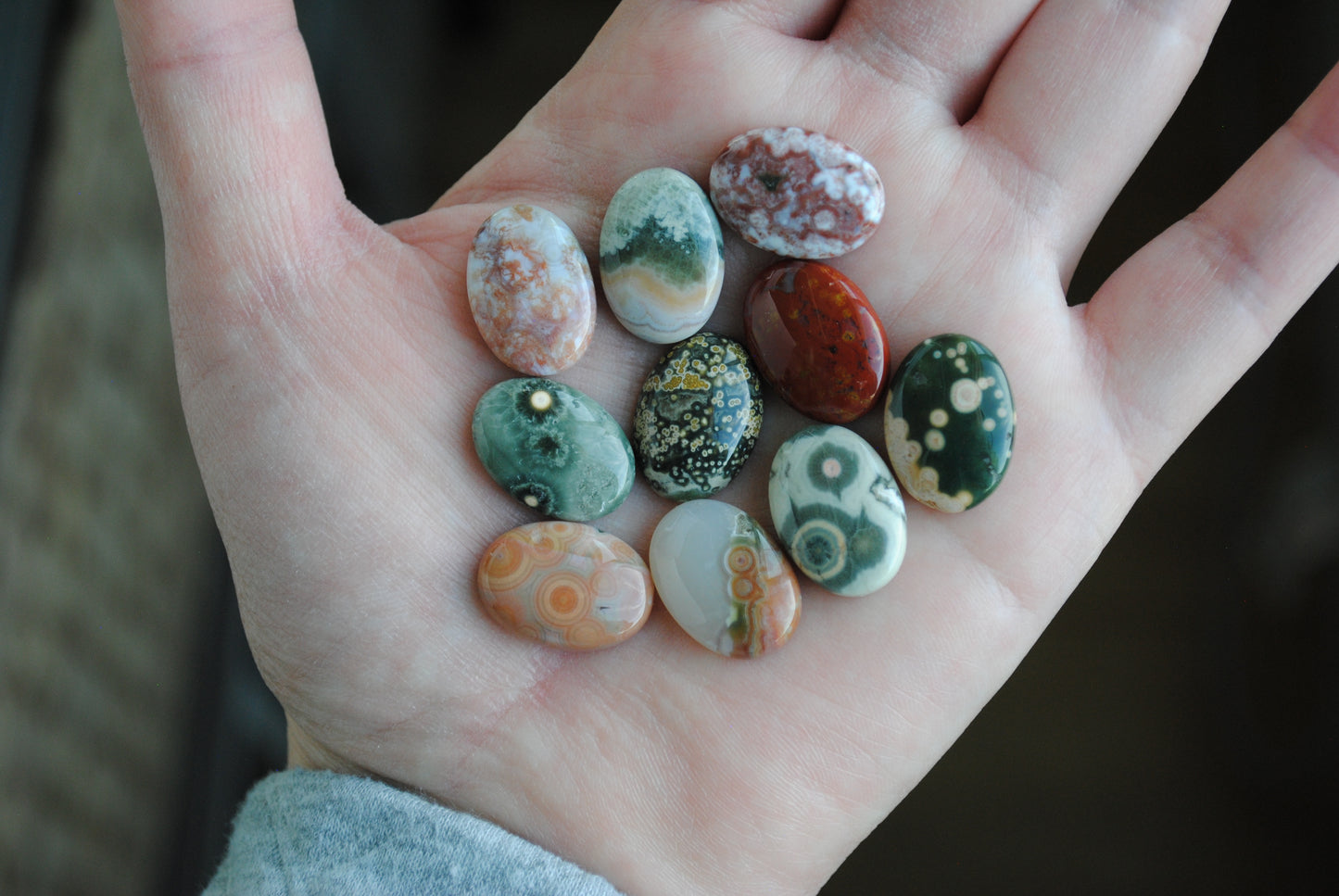 Hand holding a collection of multicolored stones with a blurred background