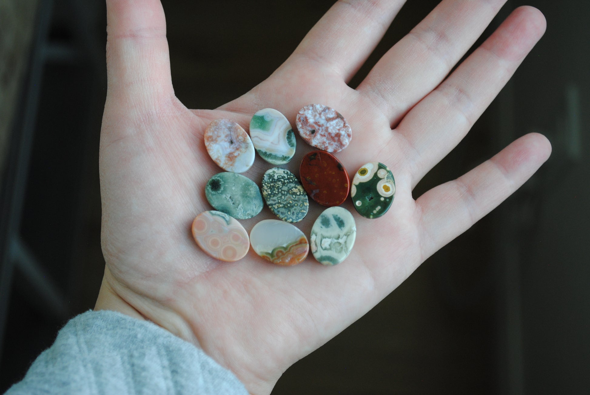 Hand holding a collection of small, colorful stones against a dark background