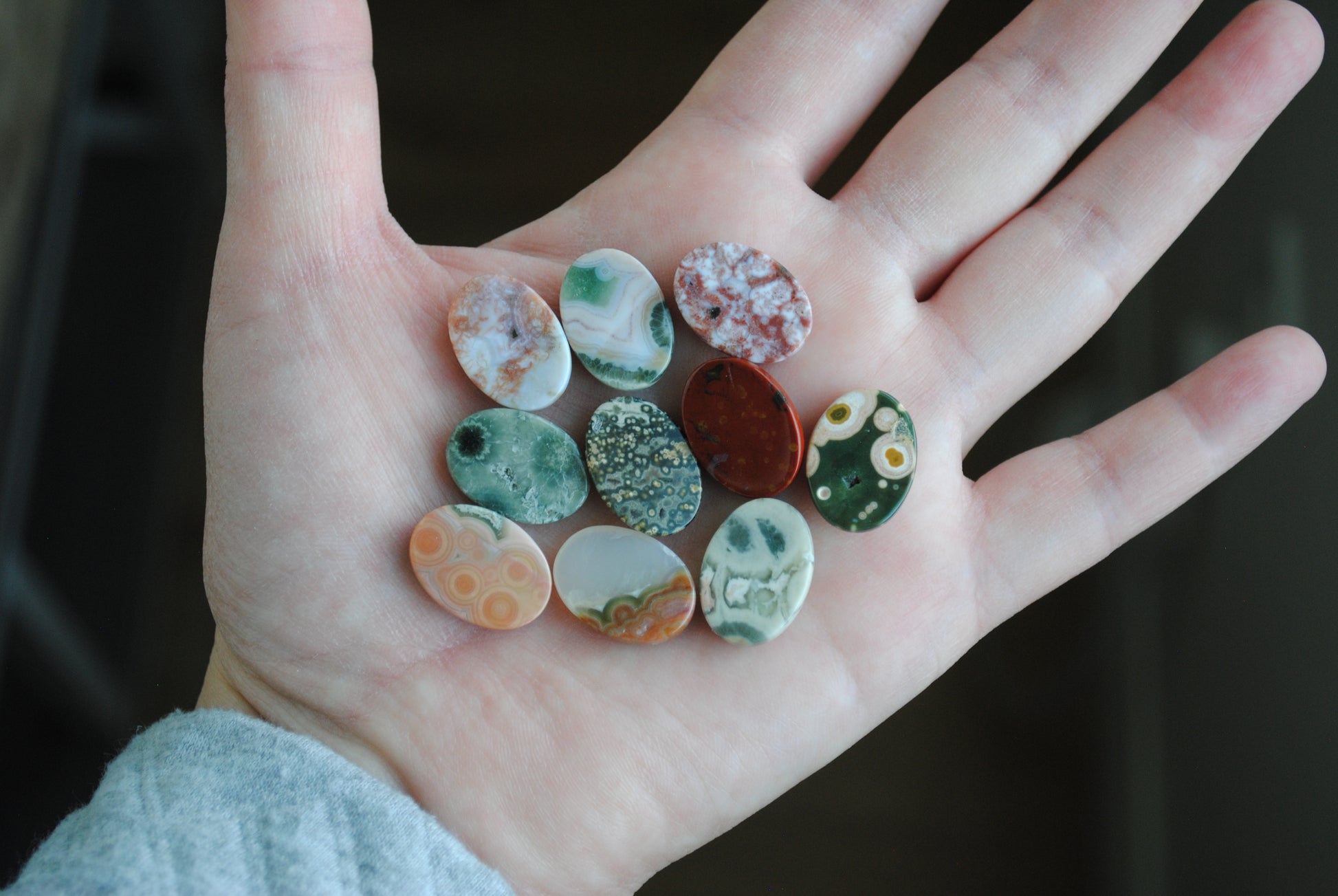 Hand holding a collection of small, colorful stones against a dark background