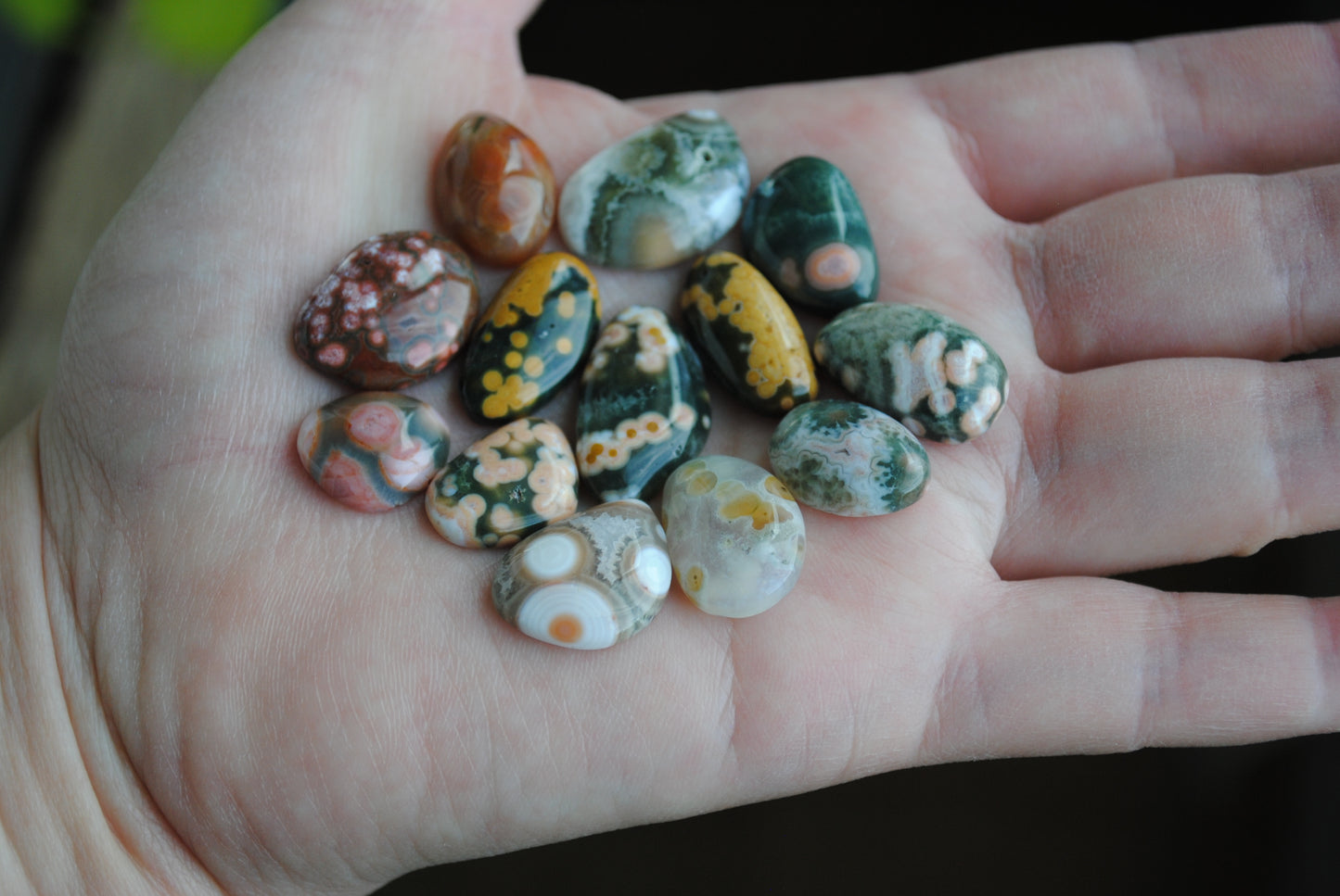 Hand holding a collection of colorful marbled stones.