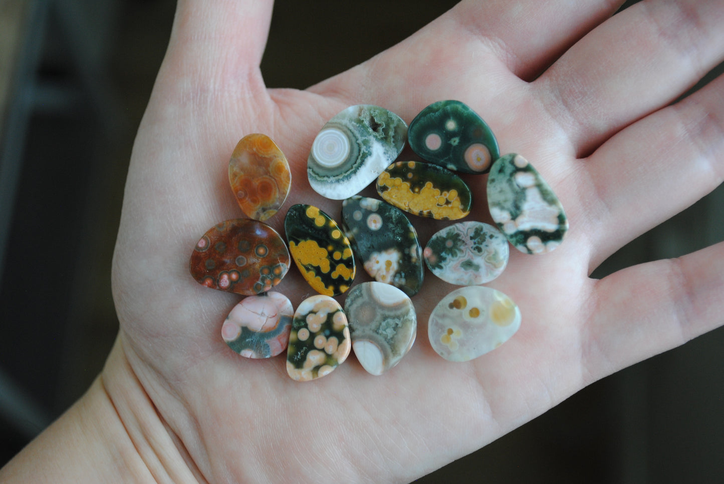 Hand holding a collection of colorful marbled stones.