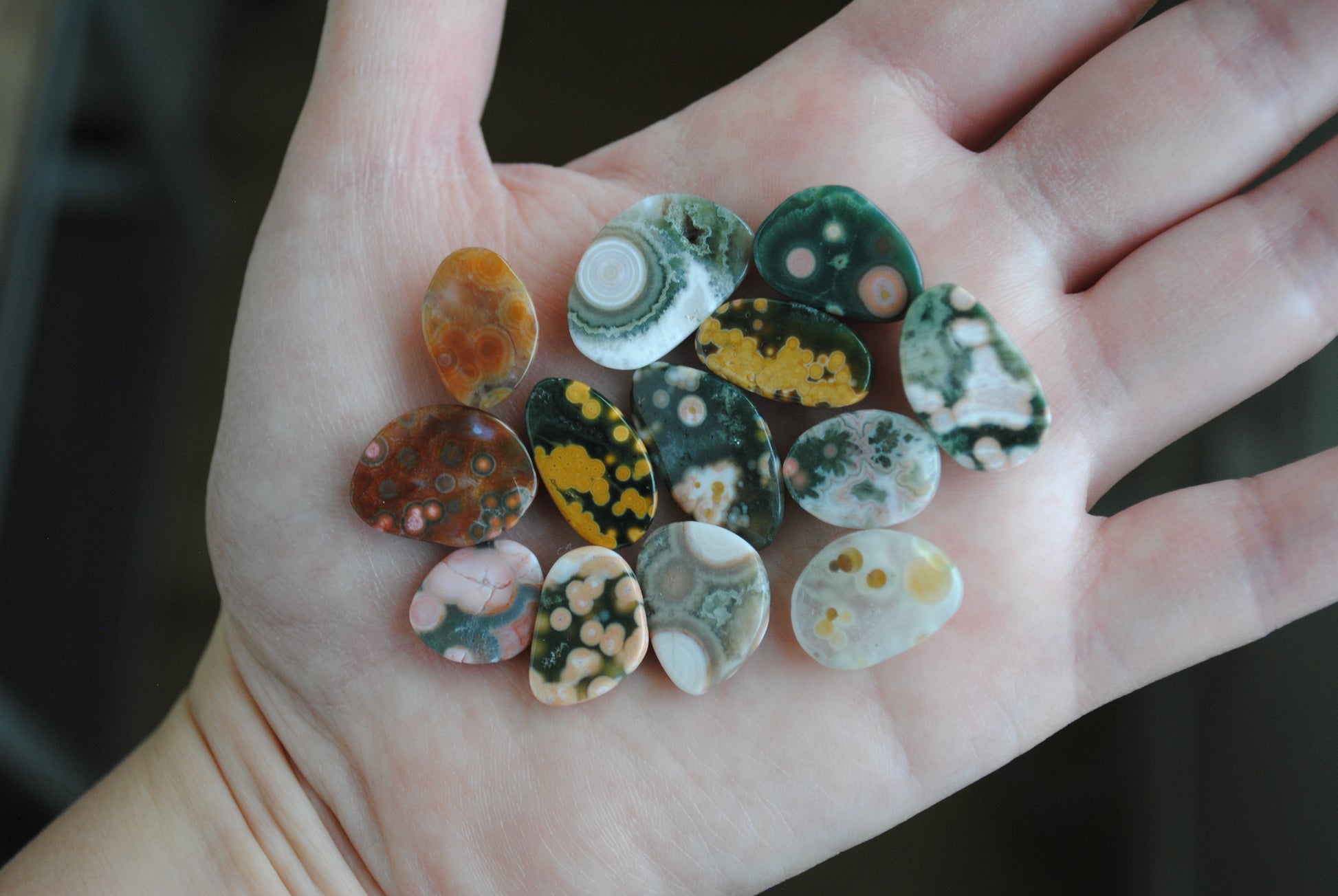 Hand holding a collection of colorful marbled stones.