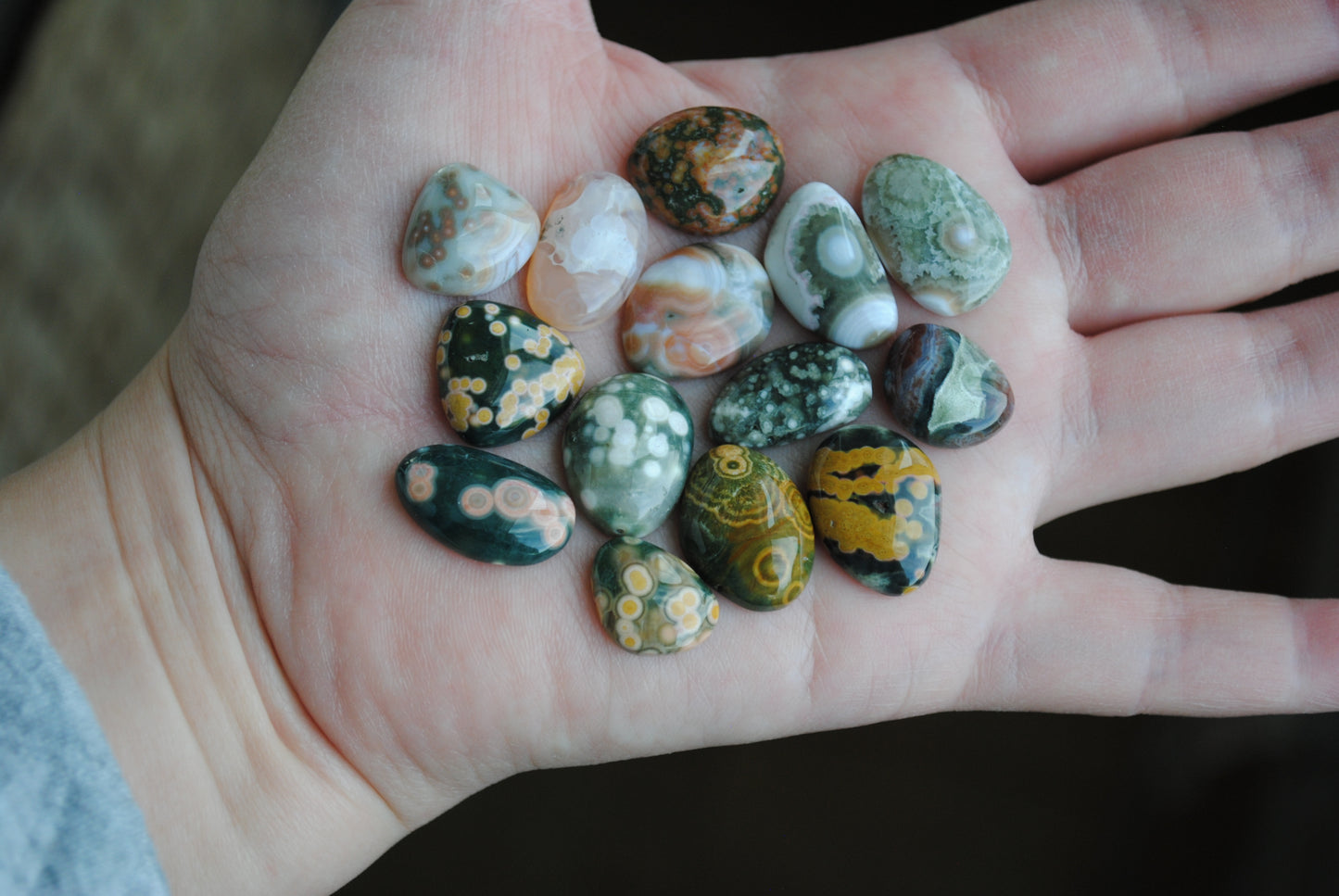 Hand holding a collection of small, multicolored stones.