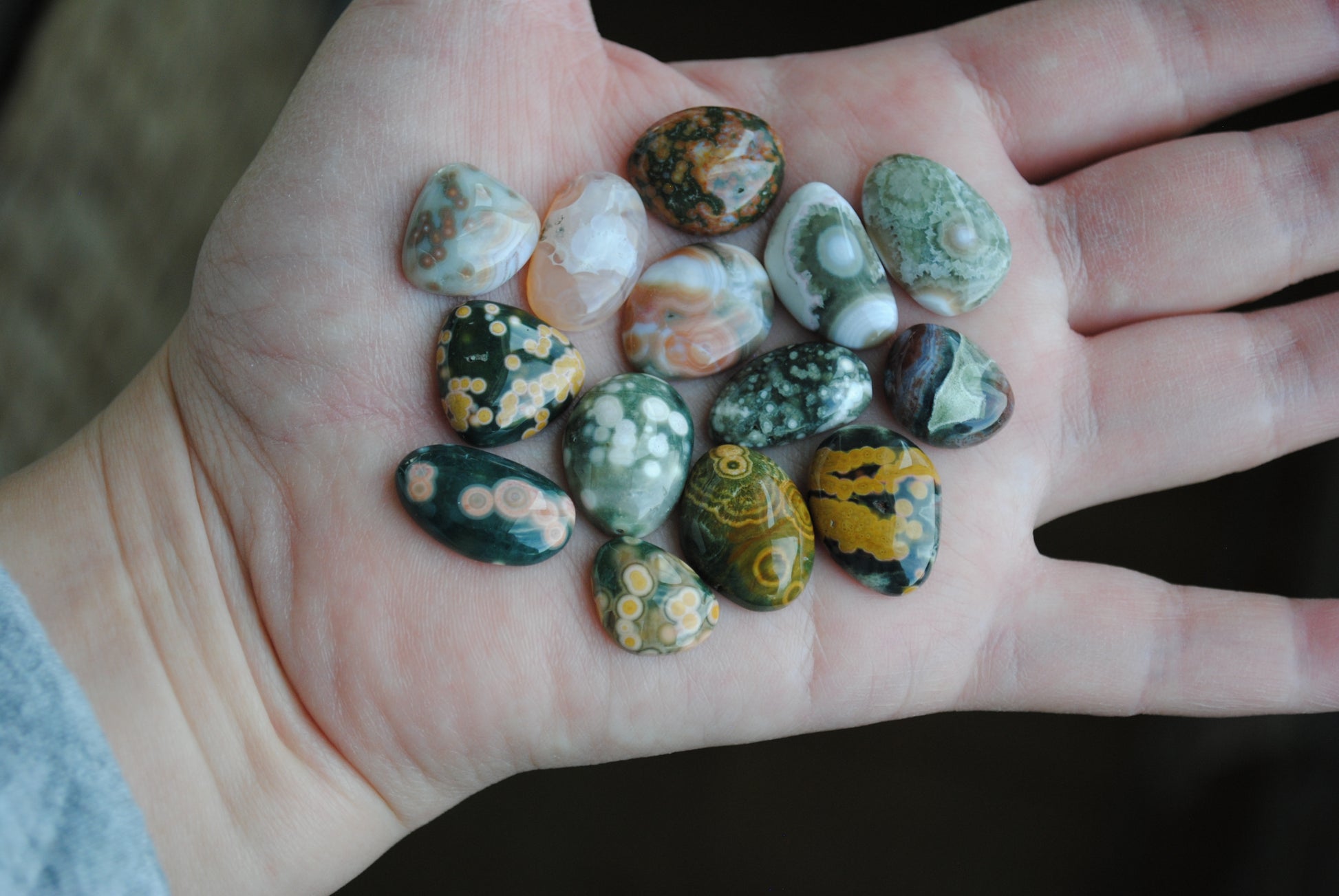 Hand holding a collection of small, multicolored stones.