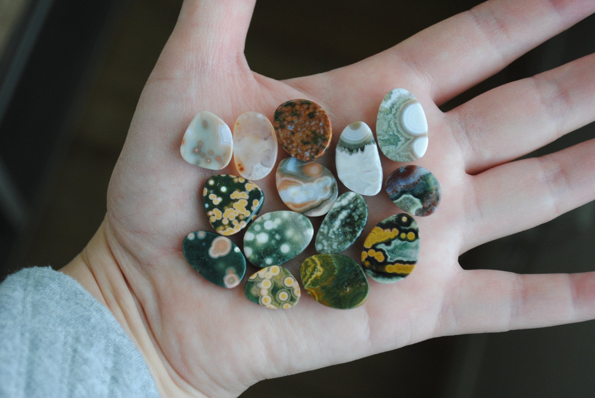 Hand holding a collection of multicolored stones with a blurred background