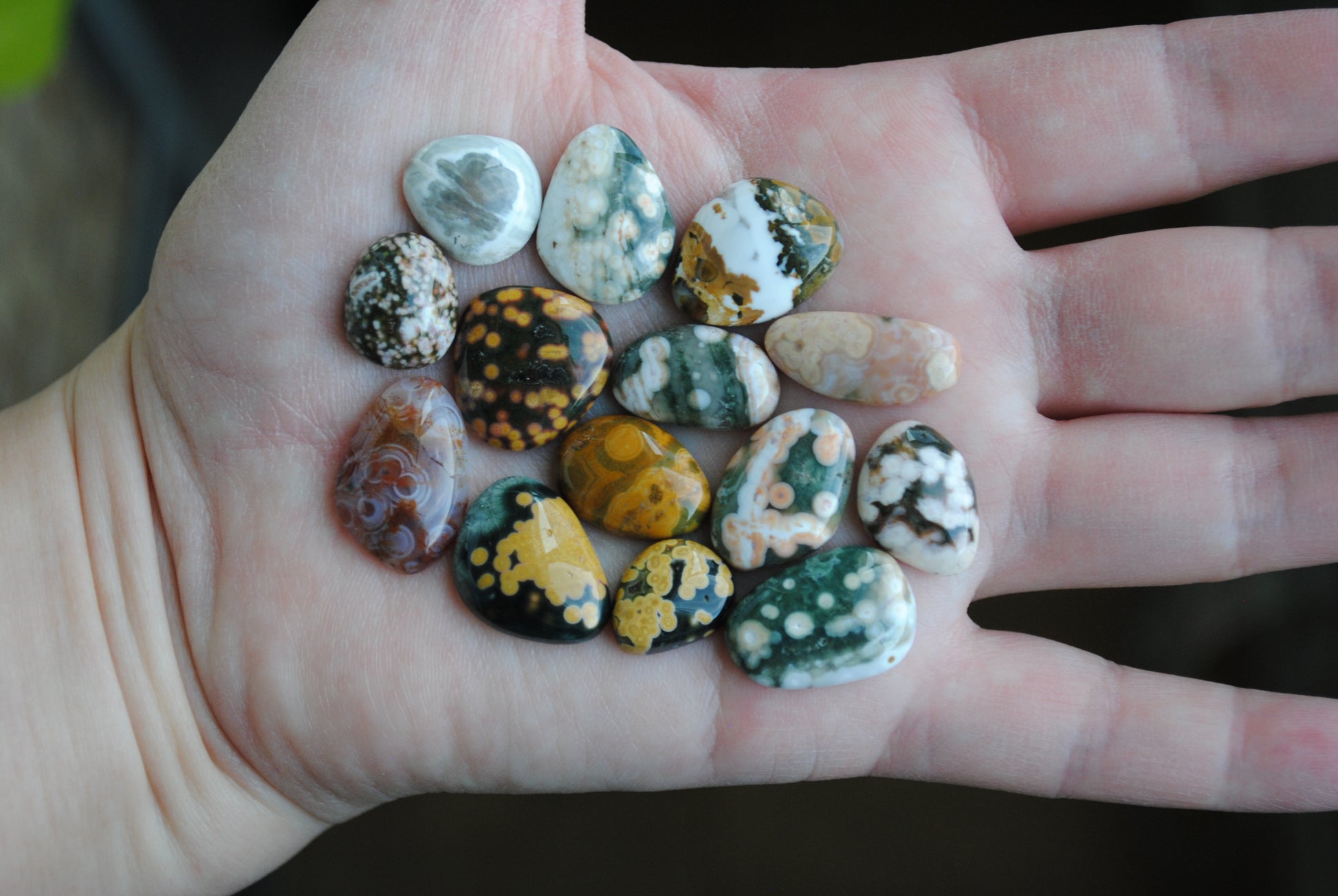 Hand holding a collection of small, multicolored stones.