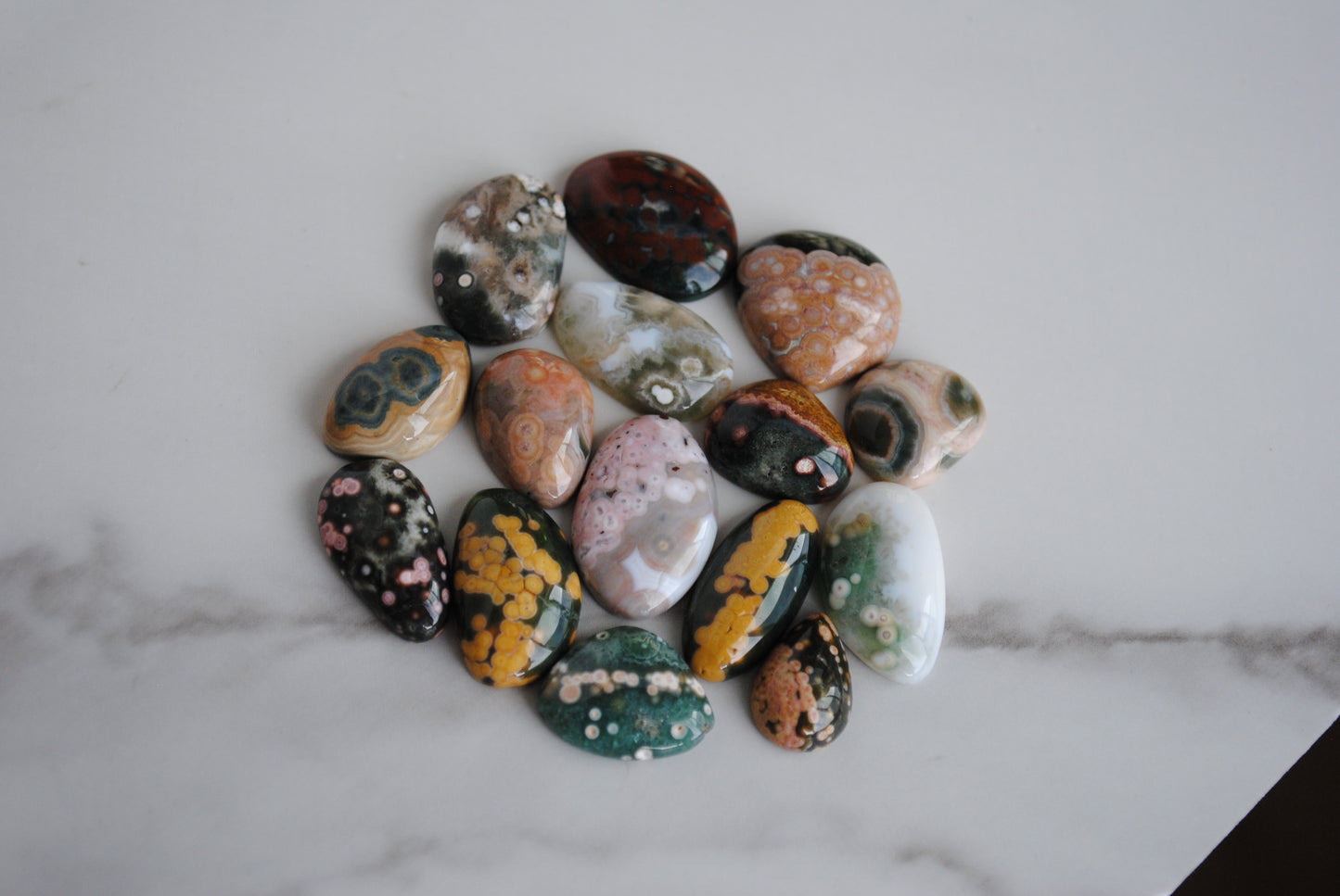 Assorted colorful stones arranged in a circular pattern on a marble surface