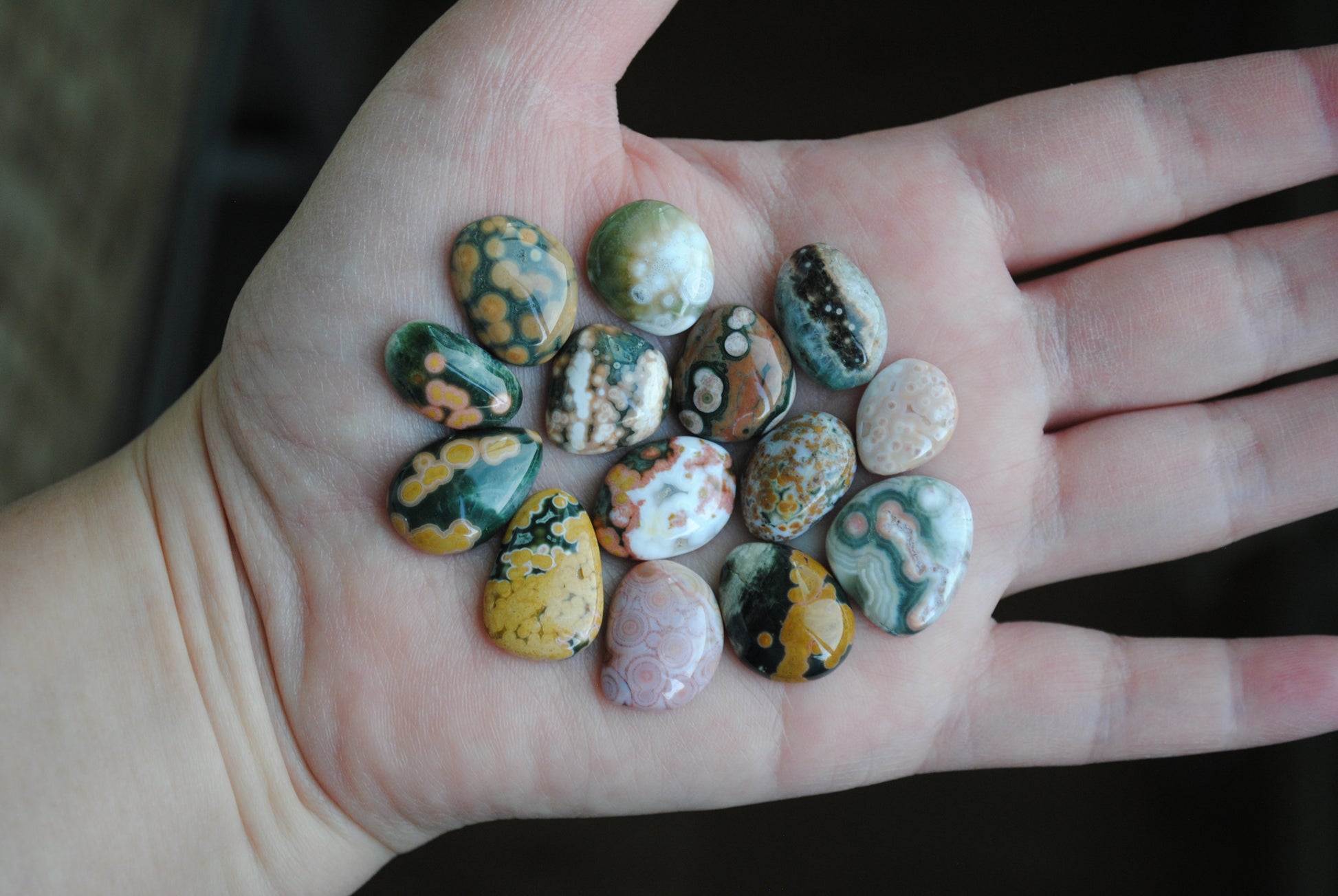 Hand holding a collection of small, multicolored stones.