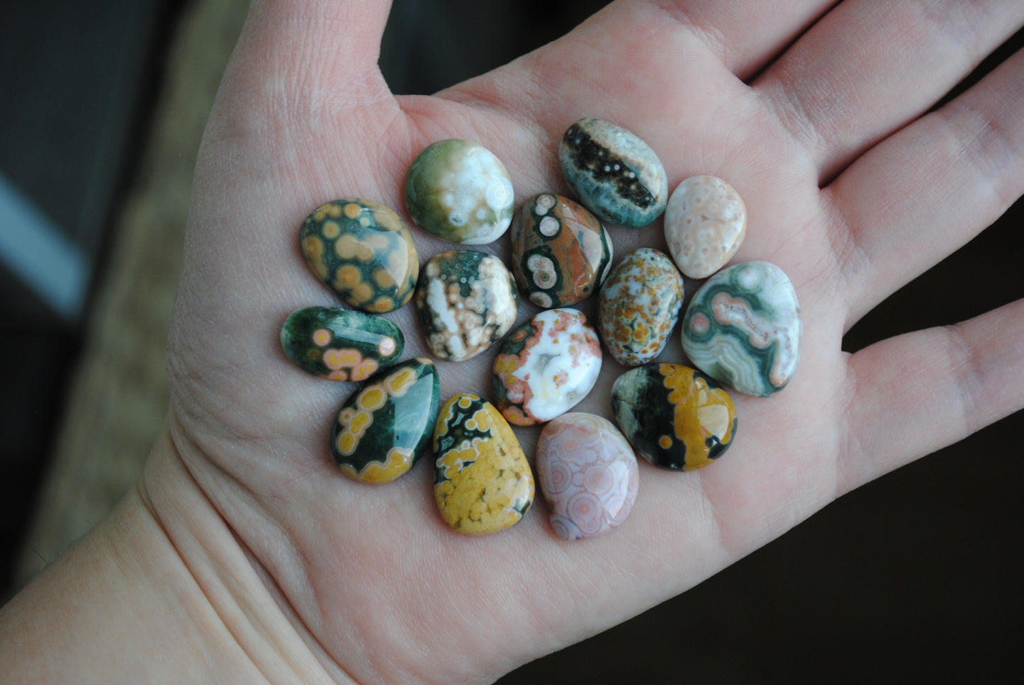 Hand holding a collection of small, multicolored stones.