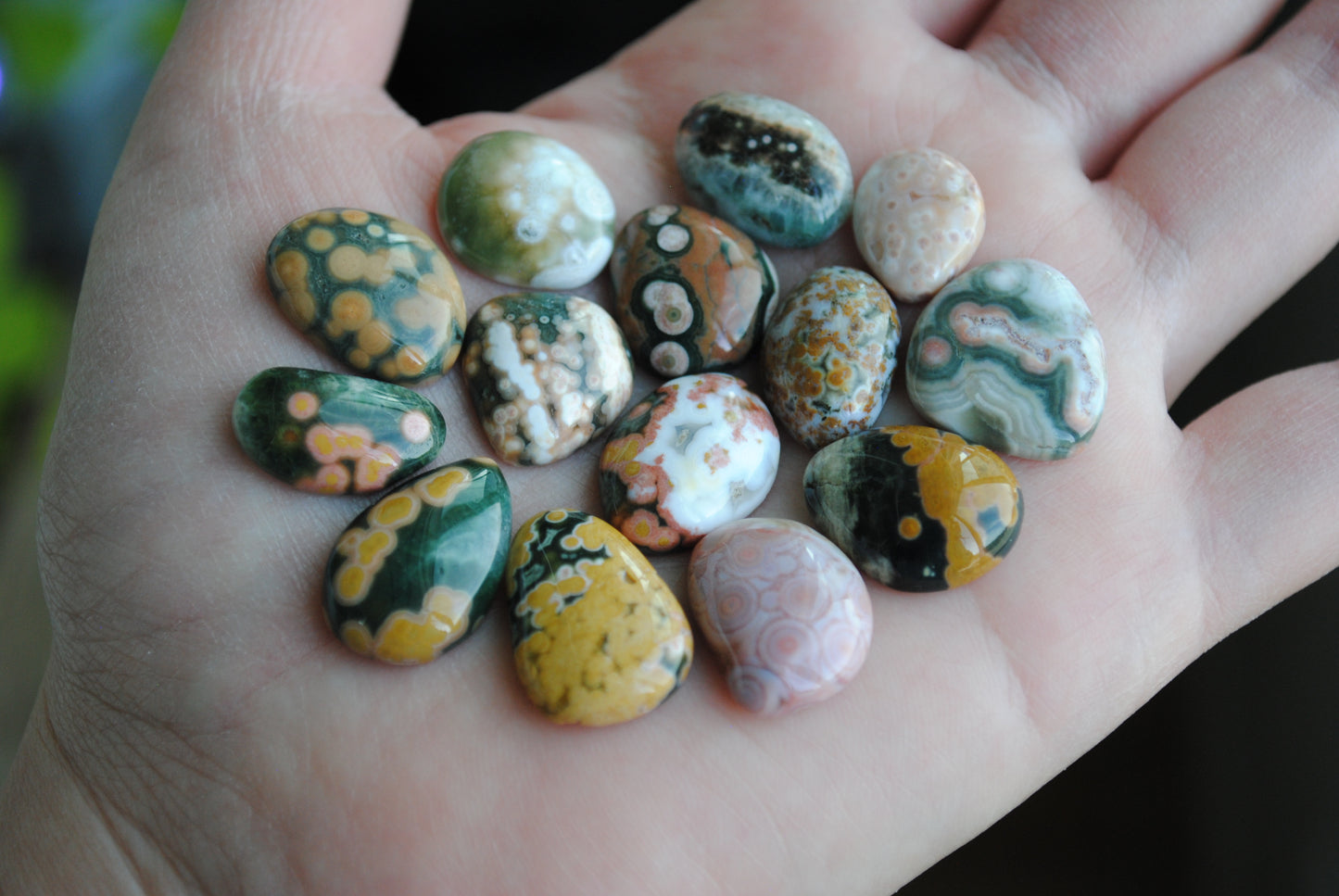 Hand holding a collection of marbled stones with various colors.