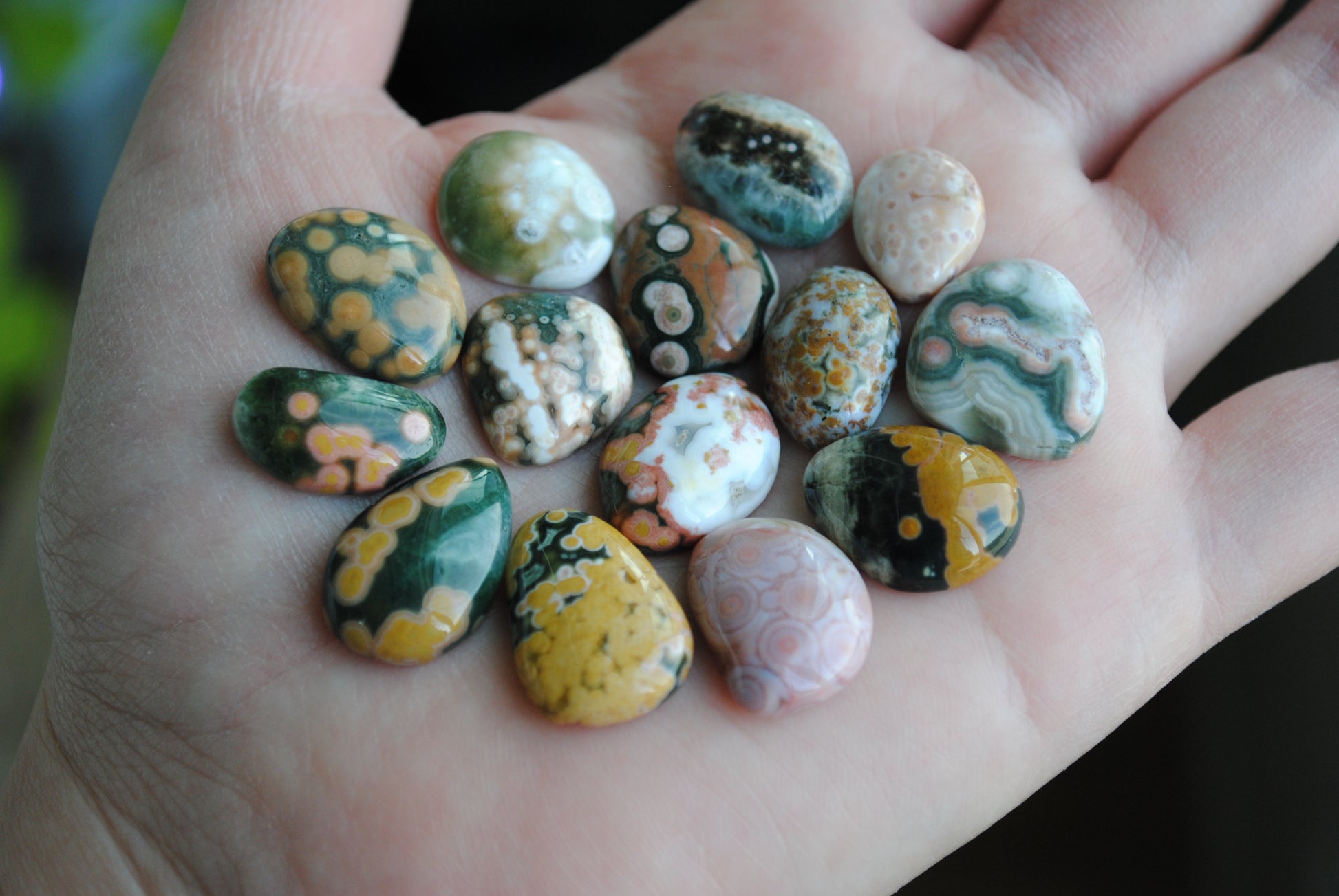 Hand holding a collection of marbled stones with various colors.