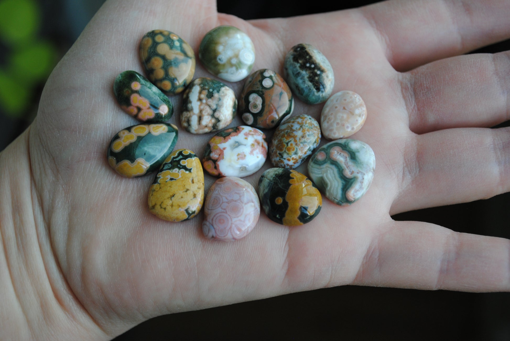 Hand holding a collection of small, multicolored stones.