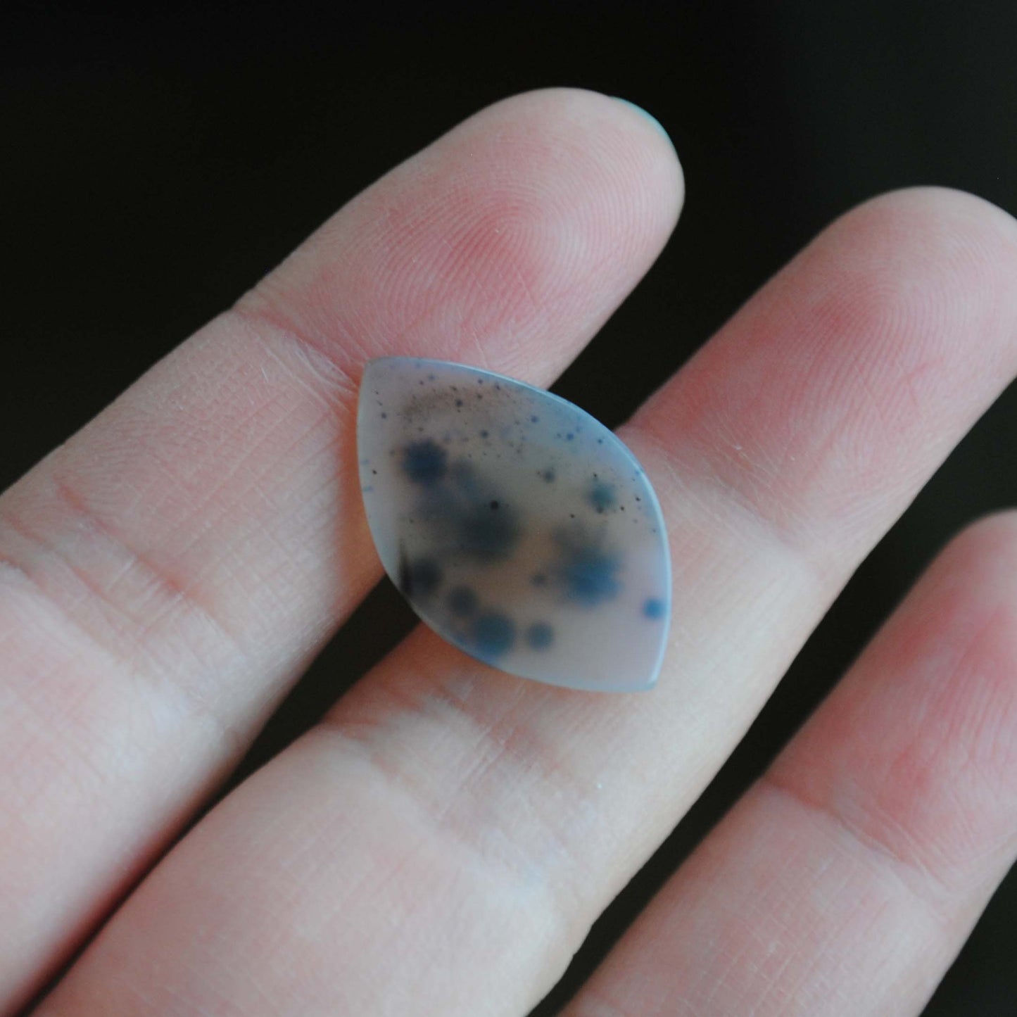 Dendritic agate stone held by fingers