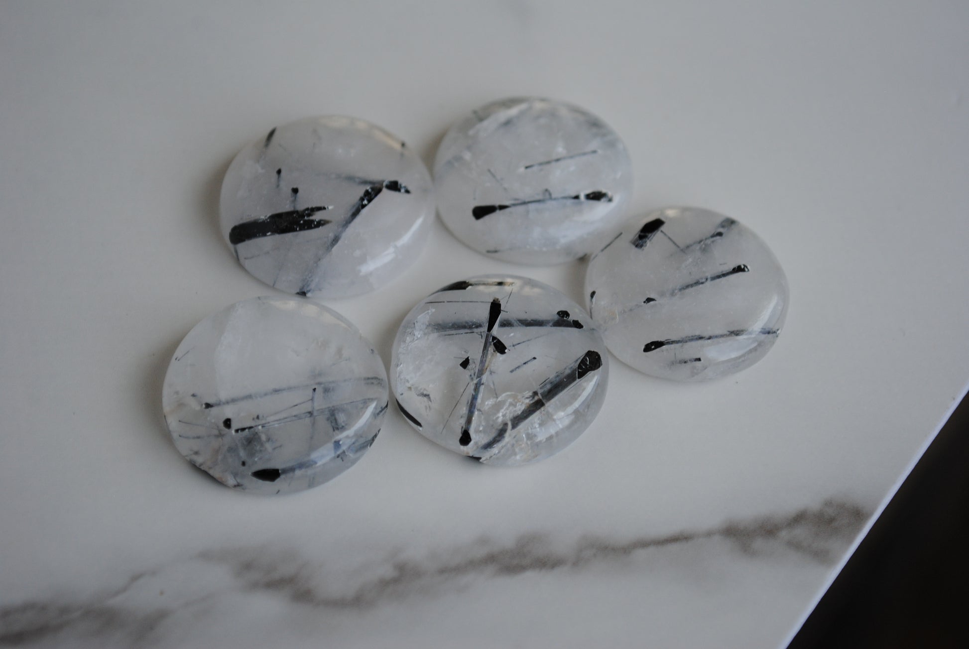Tourmalinated quartz cabochons on a light background