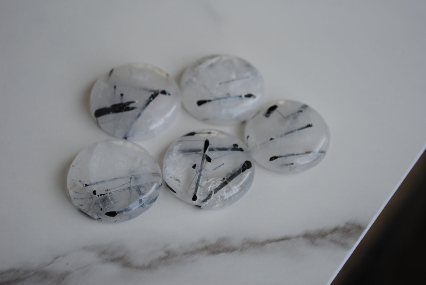 Tourmalinated quartz cabochons on a light background