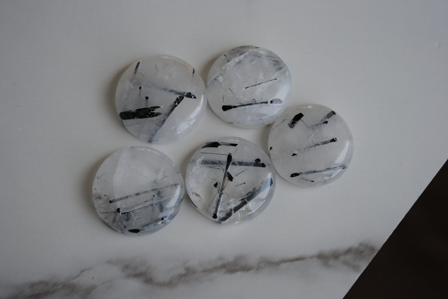 Tourmalinated quartz cabochons on a light background