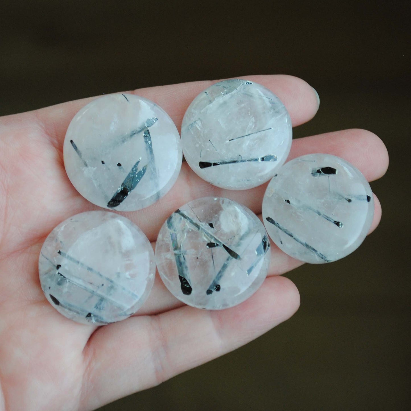 Tourmalinated quartz cabochons held in palm of hand