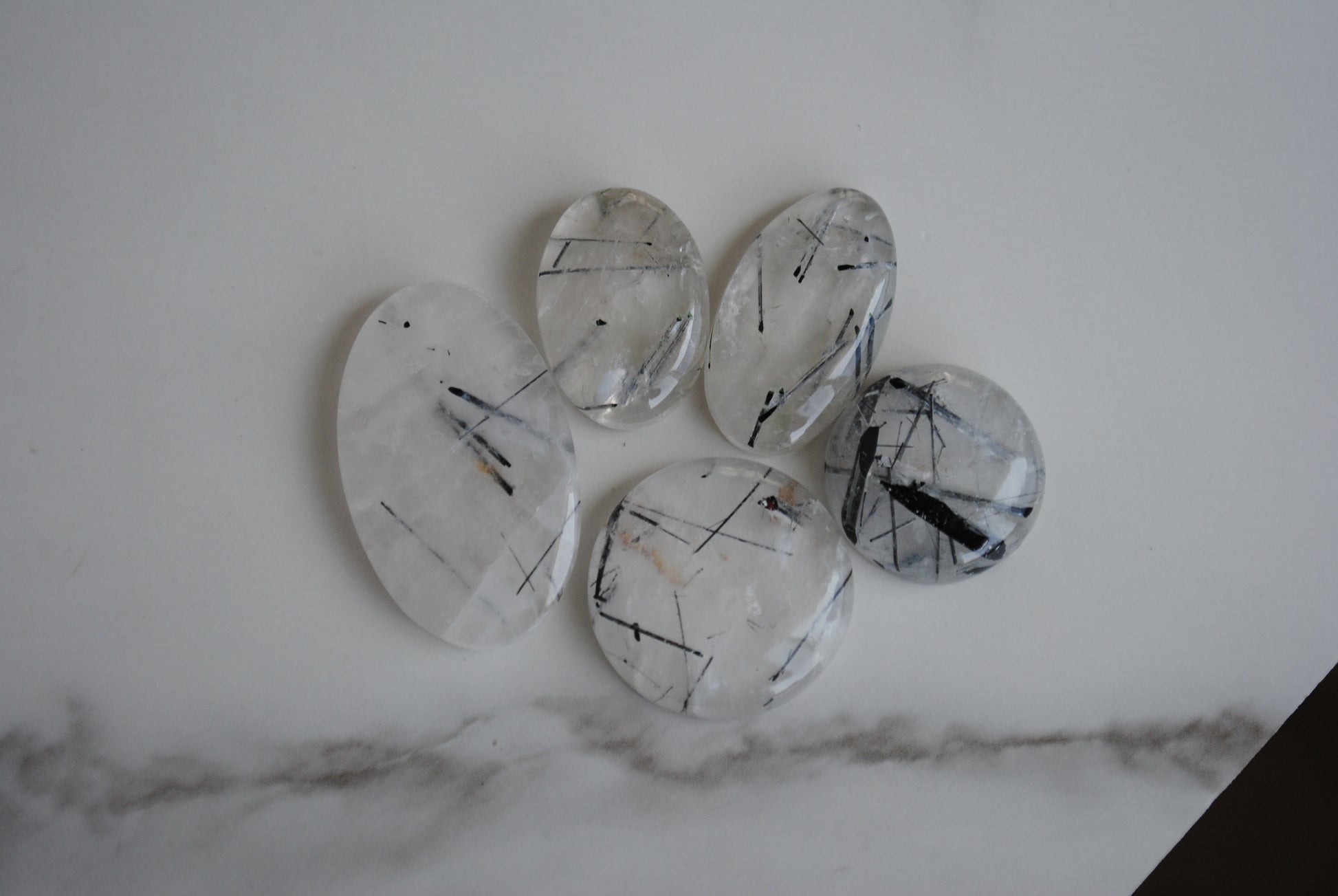 Tourmalinated quartz cabochons on light background