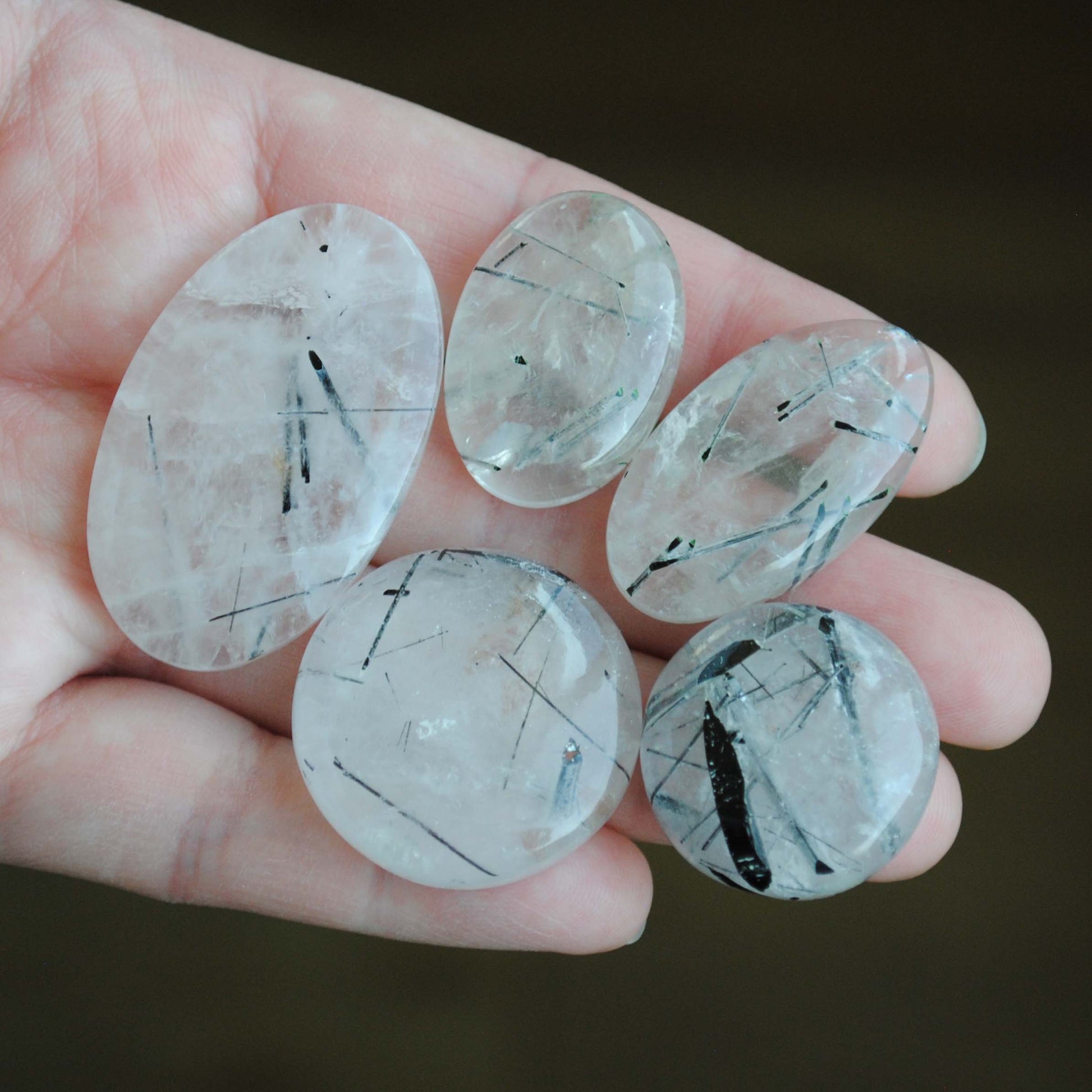 Tourmalinated quartz cabochons on palm of hand