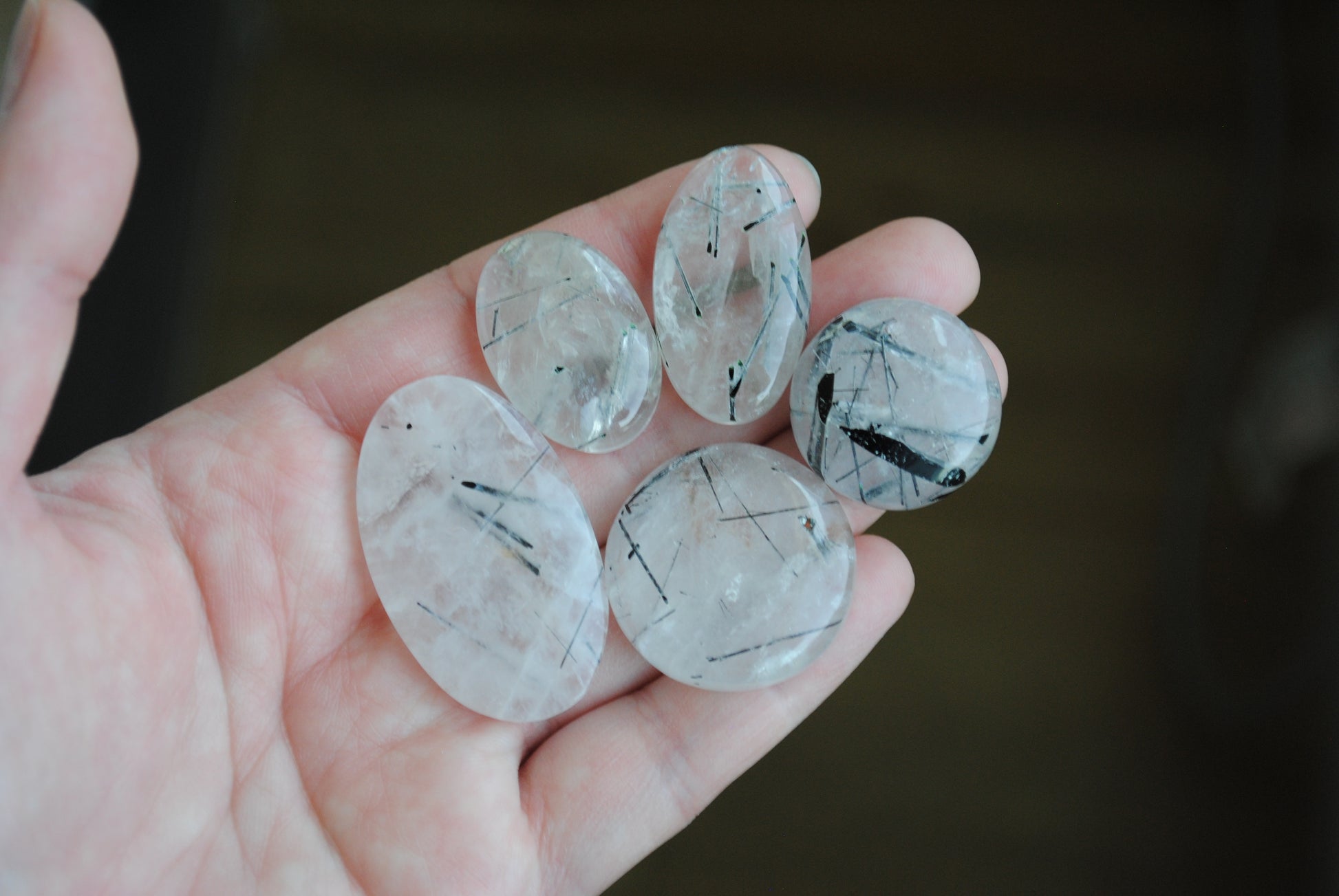 Tourmalinated quartz cabochons on palm of hand