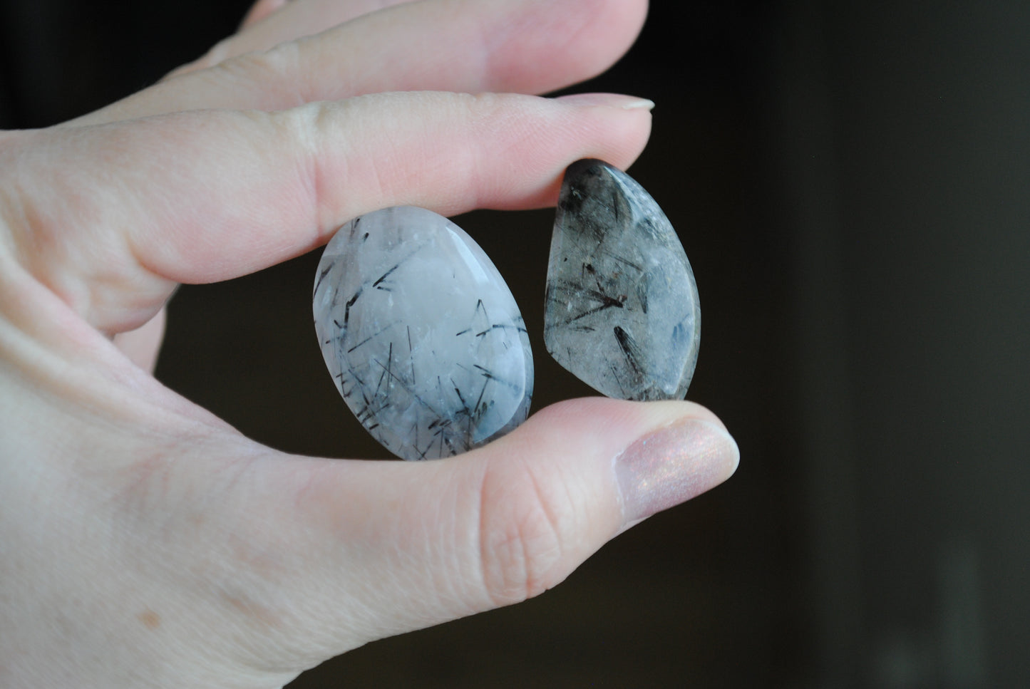 Tourmalinated quartz cabochons in fingers