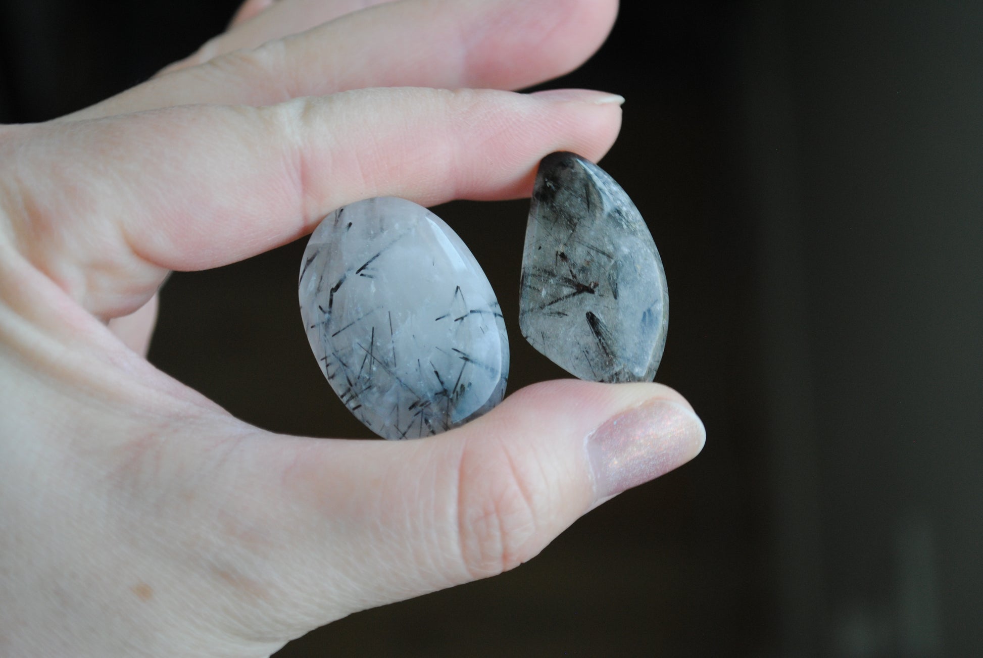Tourmalinated quartz cabochons in fingers